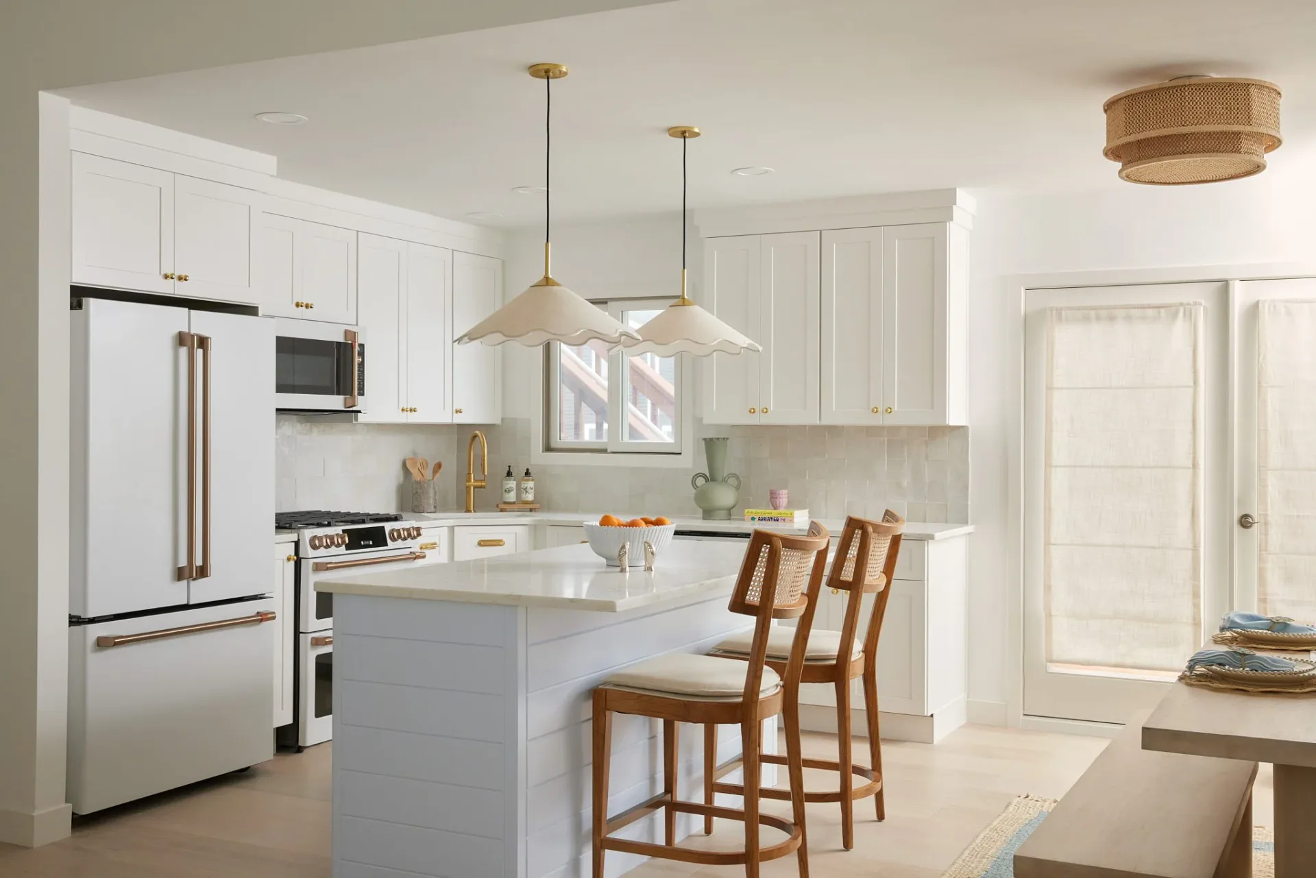 Modern kitchen with white cabinetry, gray island, stainless steel appliances, pendant lighting, and wood bar stools by Vanessa Lugo.