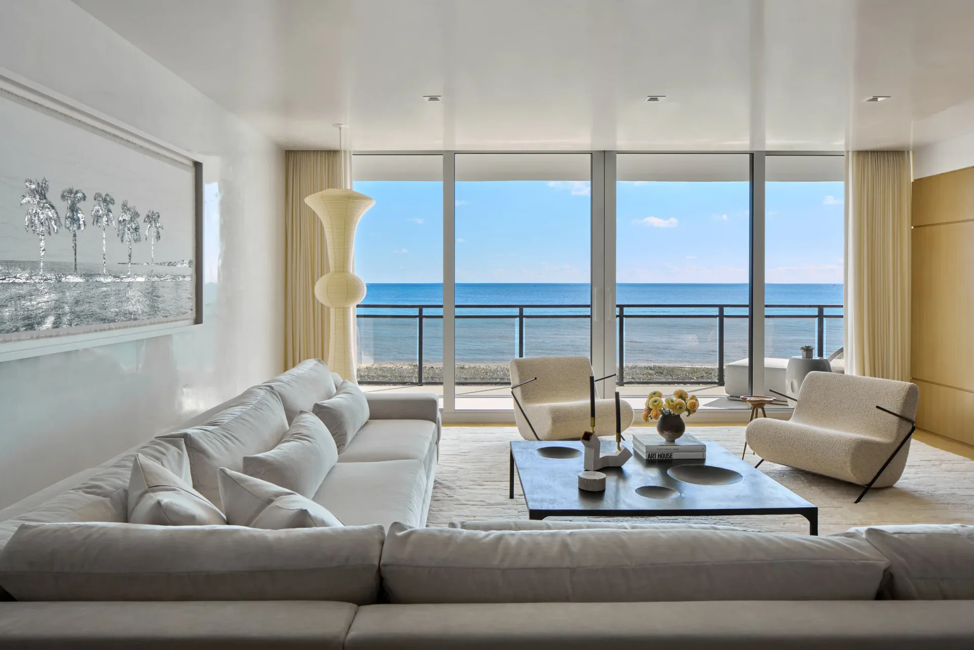 Luxurious modern oceanfront living room with floor-to-ceiling windows, neutral furnishings, and coastal views by Vanessa Rome.