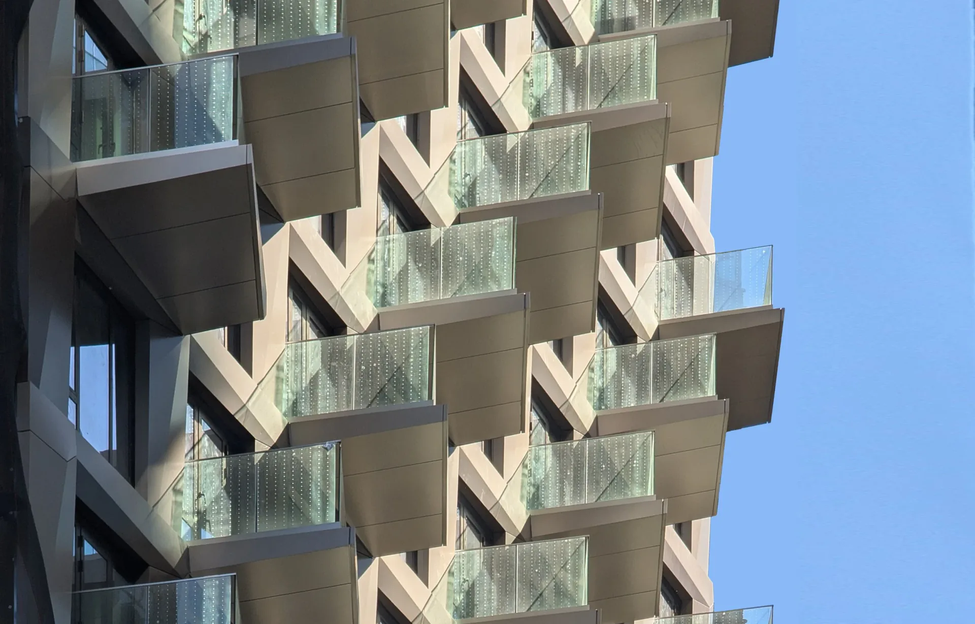Modern residential building facade with staggered concrete balconies and large glazed windows creating dynamic diagonal patterns, designed by Weilin Berkey.