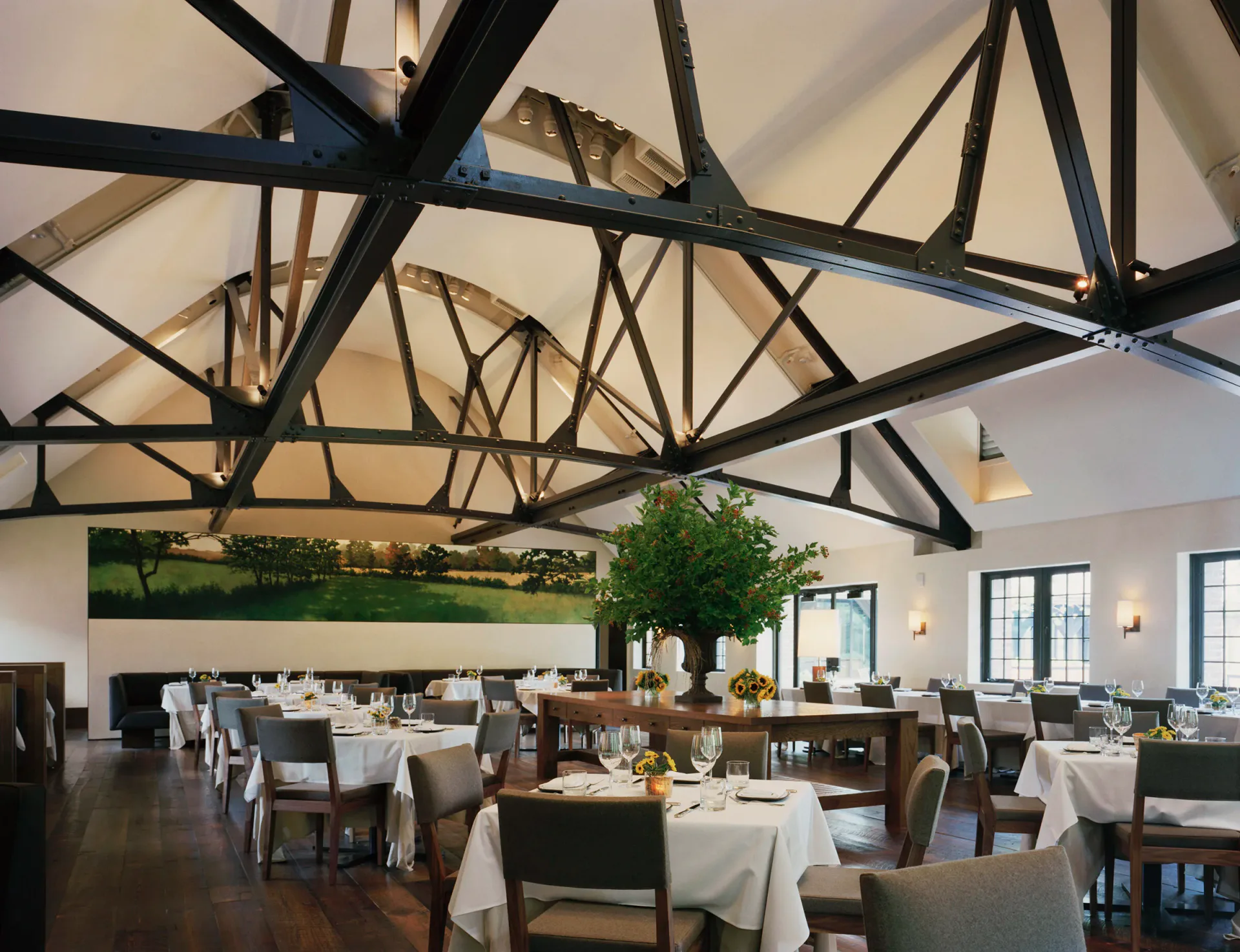 Elegant dining room with dramatic black exposed beam ceiling, white walls, living green wall installation, and formally set tables with white linens by William Armstrong.