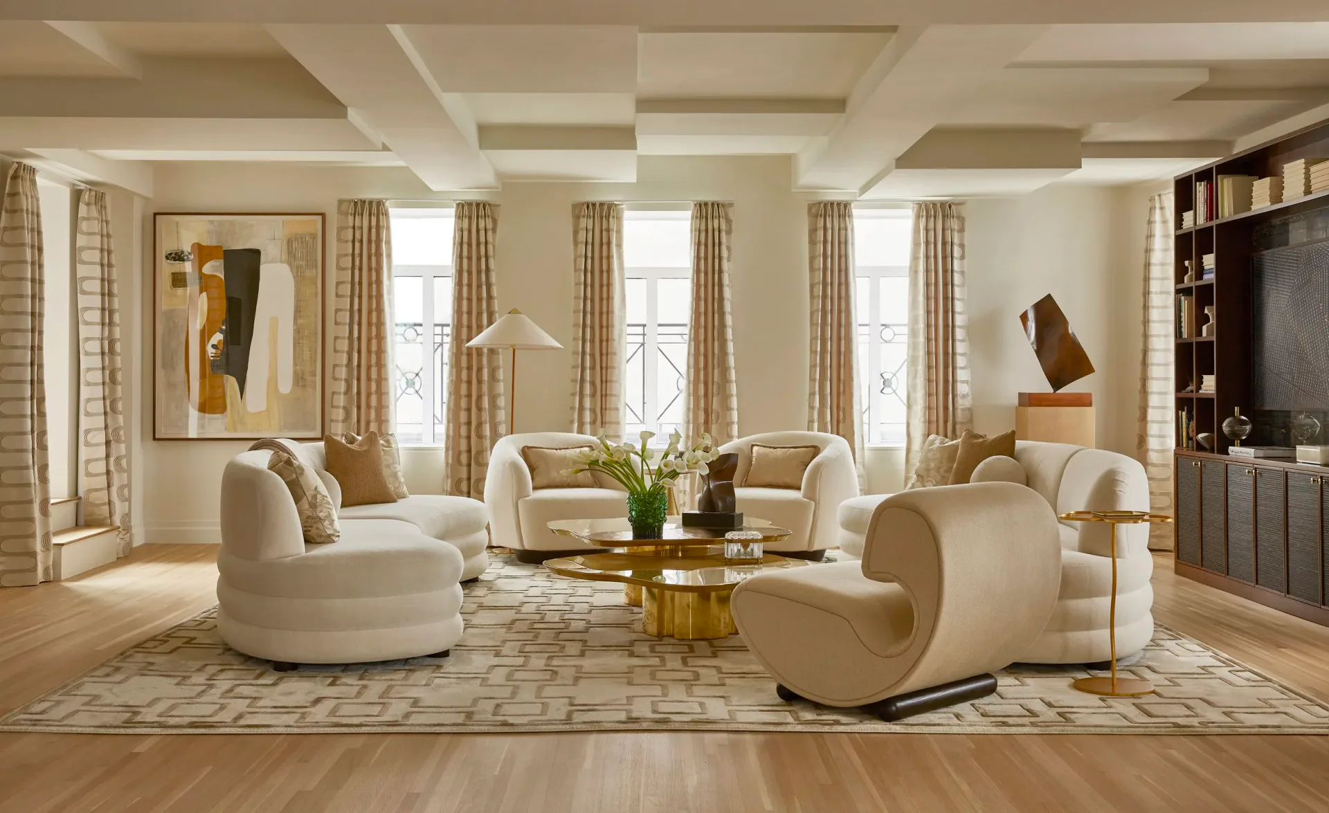 Luxurious cream-toned living room with curved furniture, coffered ceiling, and golden accents by Young Huh.