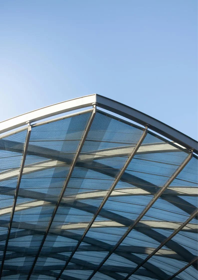 Modern architectural canopy featuring geometric steel framework with translucent blue polycarbonate panels creating dramatic shadows against clear sky, by Zaur Gurbanaliyev.