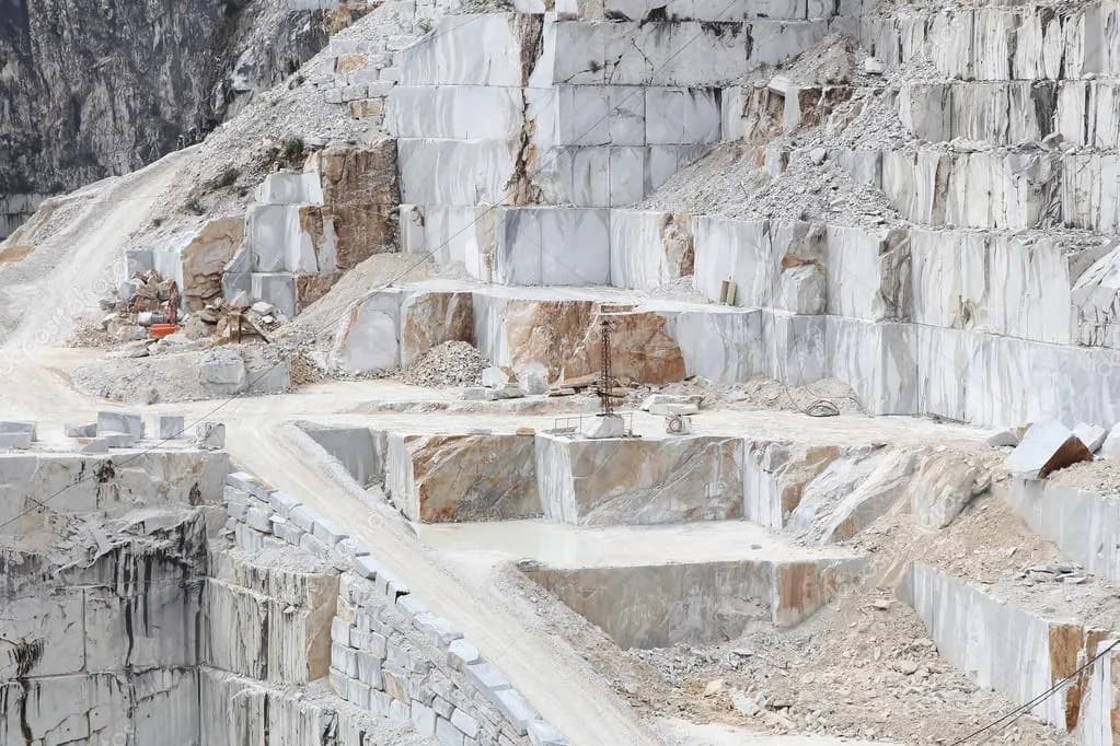 Marble quarry with white and tan stone blocks extracted in geometric formations, showcasing natural stone sourcing and processing by 29 Street Stone Inc.