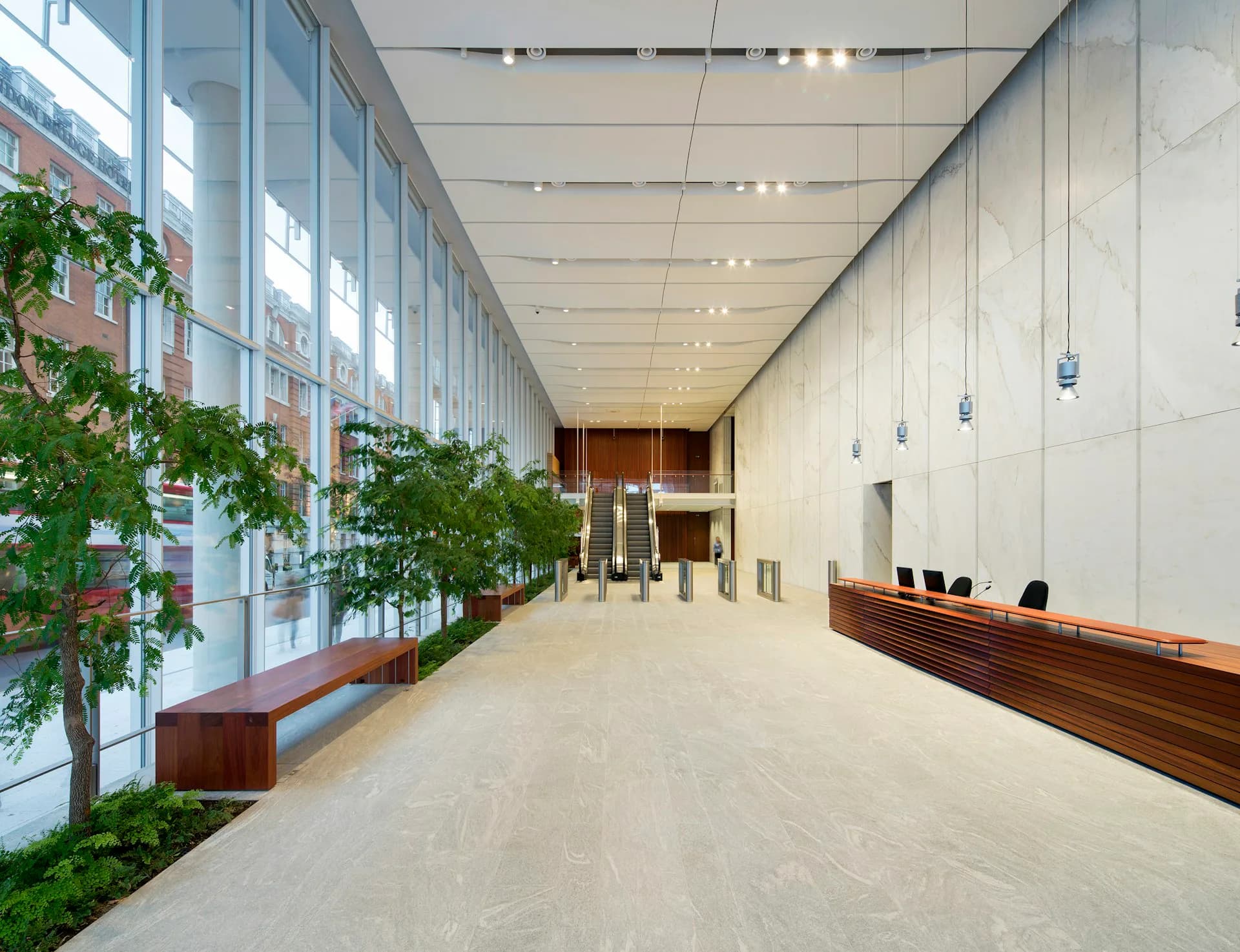 Modern office lobby with polished concrete flooring, floor-to-ceiling glazing, living plant wall, and wooden reception desk by Adamson Associates Architects.