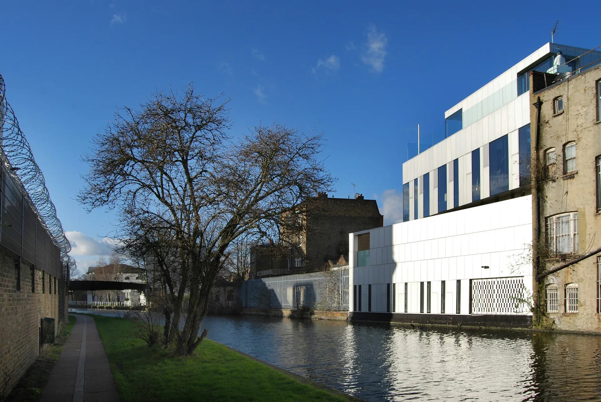 Contemporary white and blue residential building with stone facades reflected in canal water, surrounded by period architecture, designed by Adjaye Associates.