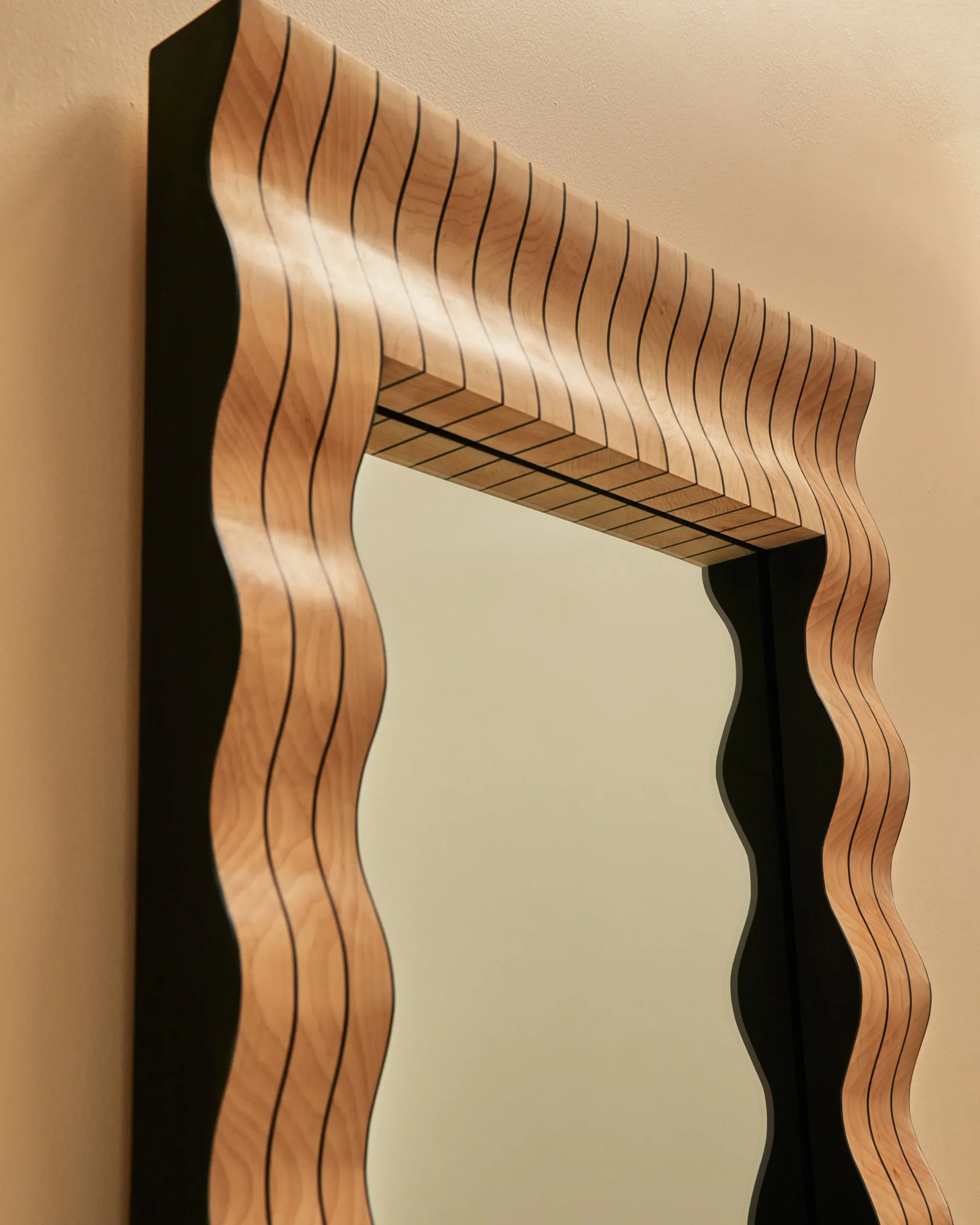 Curved wooden frame with undulating wavy edges in natural light wood tones against a pale wall by Alexis & Ginger.