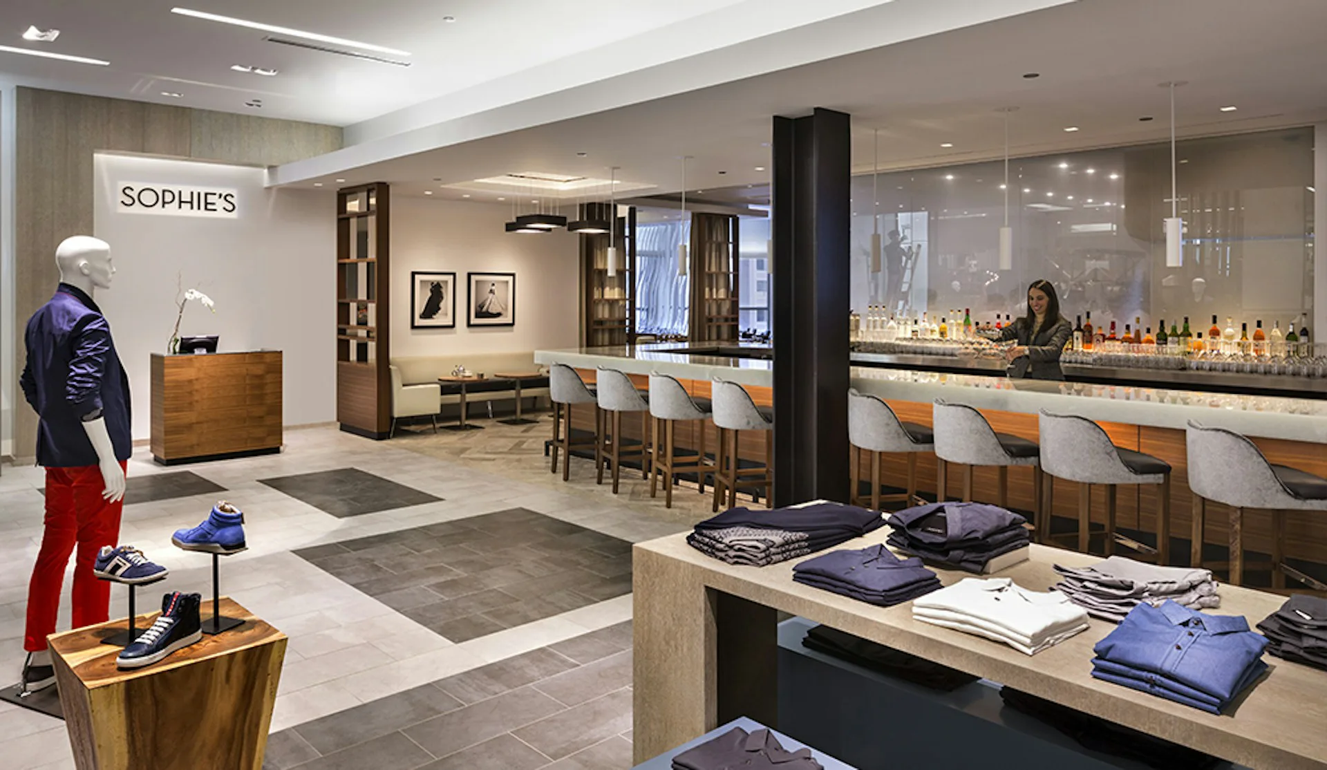 Sophie's retail interior featuring a modern reception area with wood cabinetry, display shelving, and bar seating with upholstered chairs by Andre Kikoski Architect.