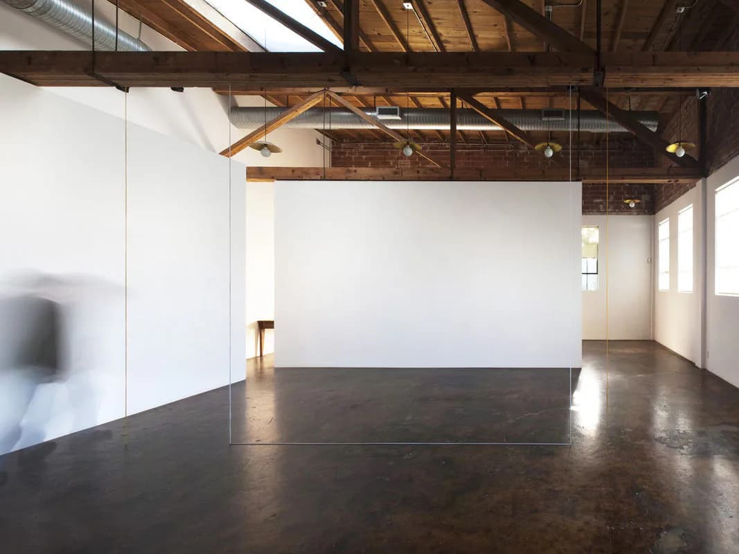 Industrial loft interior with polished concrete floors, white walls, exposed wooden ceiling trusses, and large windows by Andrew Berman Architect.