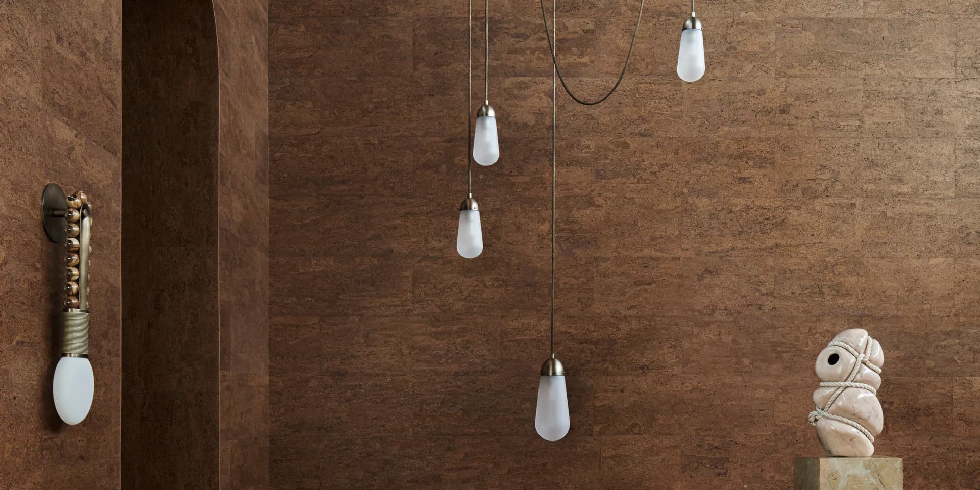 Warm terracotta interior with suspended white ceramic pendant lights and sculptural elements, showcasing lighting design by Apparatus.
