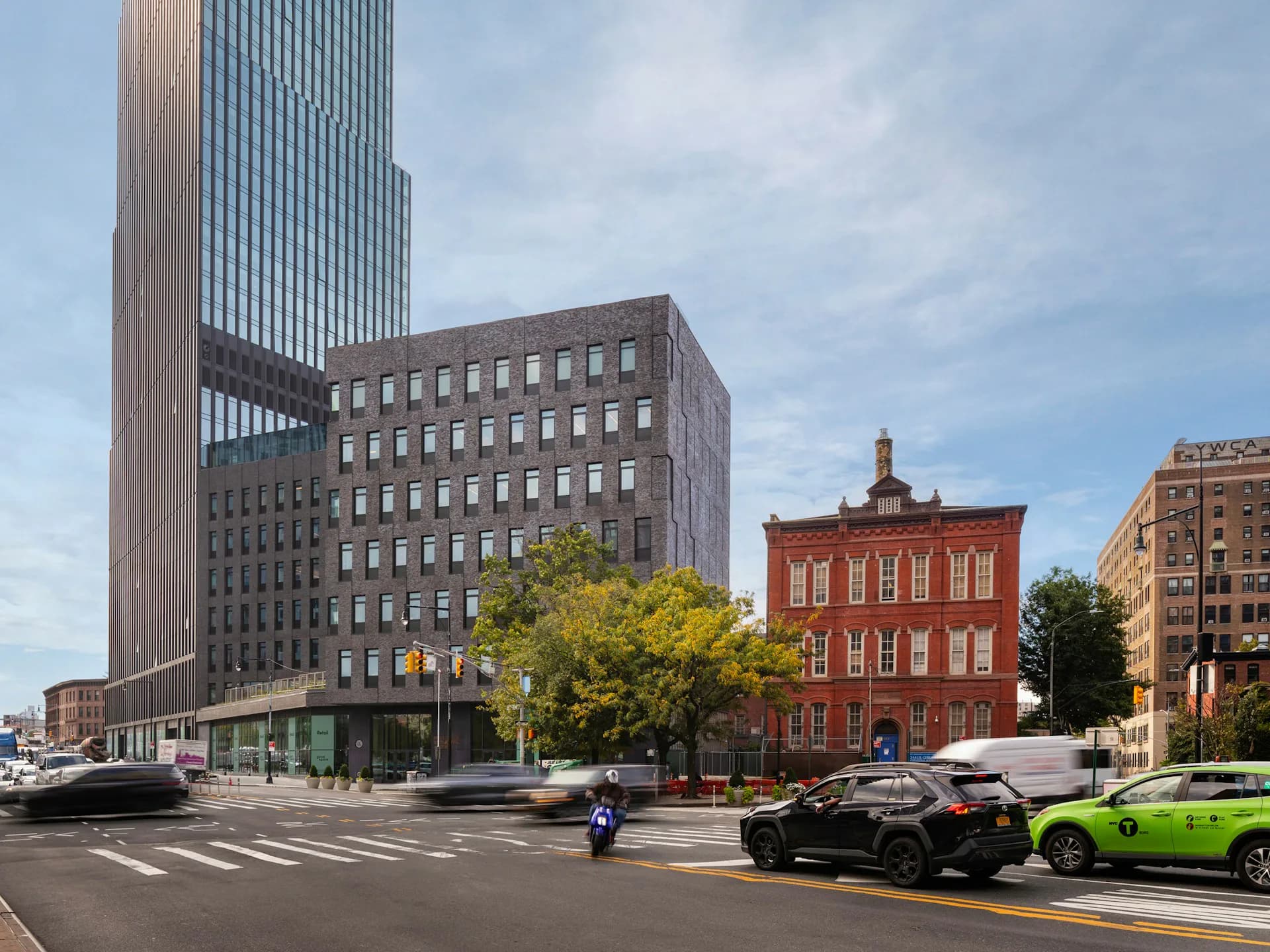 Urban street corner featuring a tall modernist tower, historic brick buildings, and a red brick structure, photographed by Architecture Research Office.