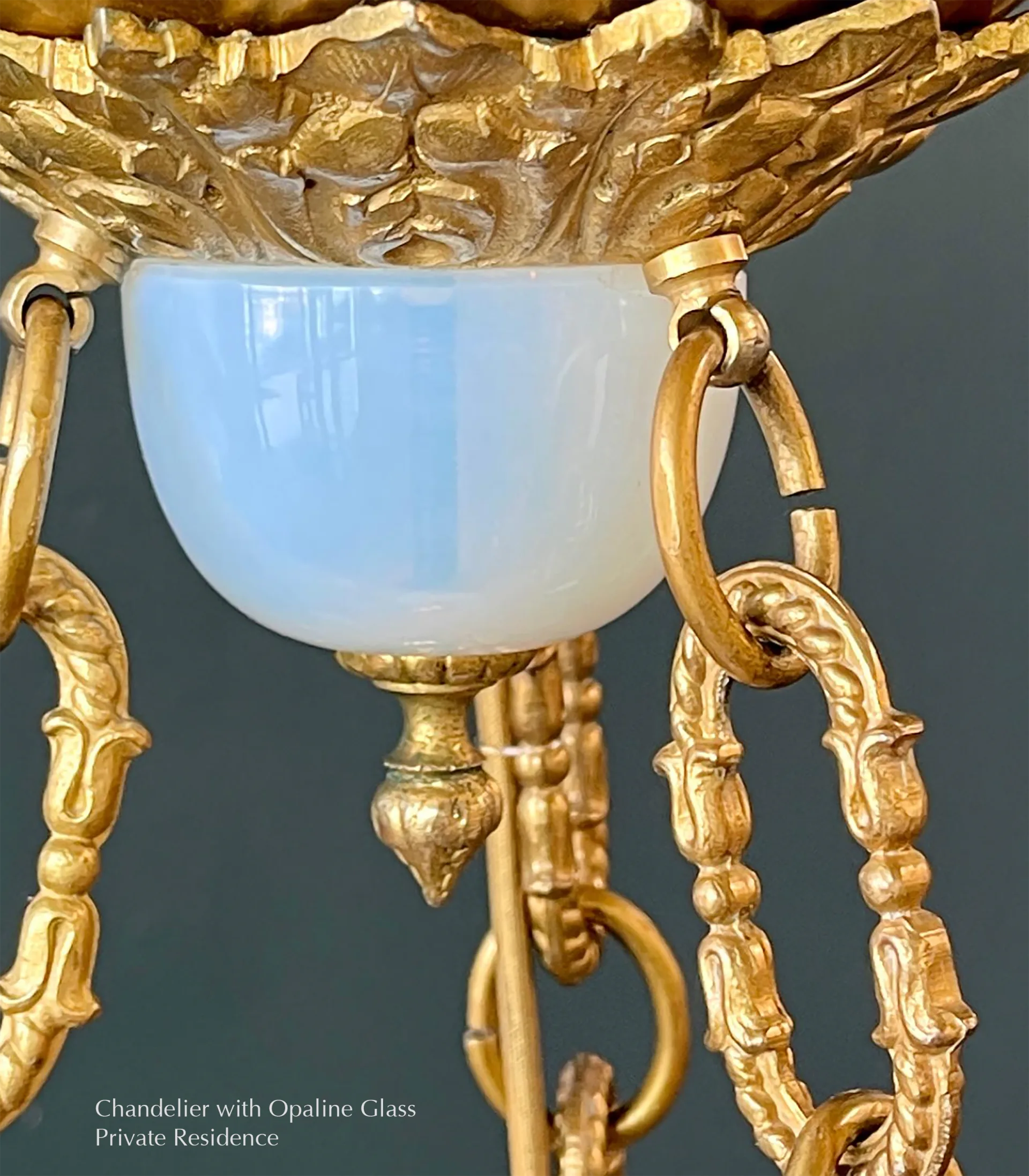 Ornate brass chandelier with opaline glass bowl and decorative chain links suspended against a neutral background by Aurora Lampworks.