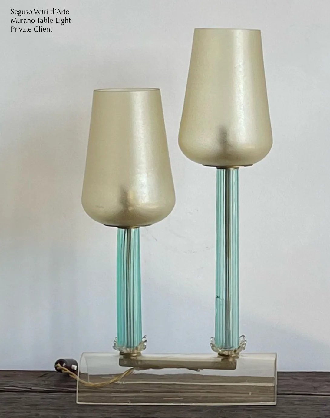 Two-lamp table light with fluted glass stems and warm metallic glass shades by Aurora Lampworks, mounted on a rectangular base.