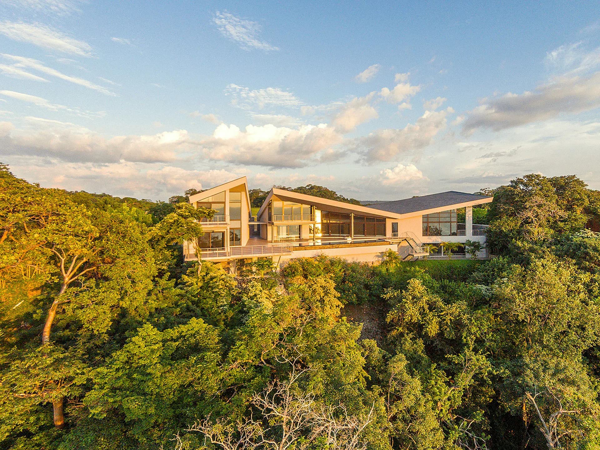 Modern residential architecture nestled in lush forest canopy, featuring warm-toned timber and glass design with mountain views by Barnes Coy Architects.