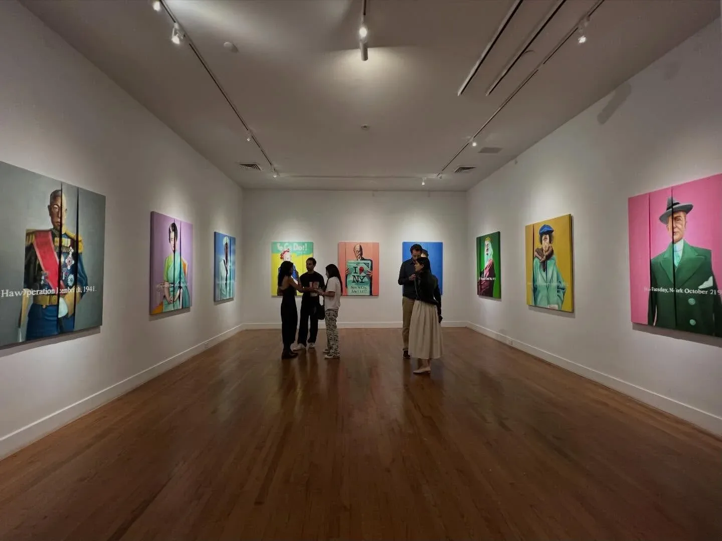 Contemporary art gallery with polished wood floors, white walls, and colorful pop art portraits by various artists displayed under track lighting by Barronarts.