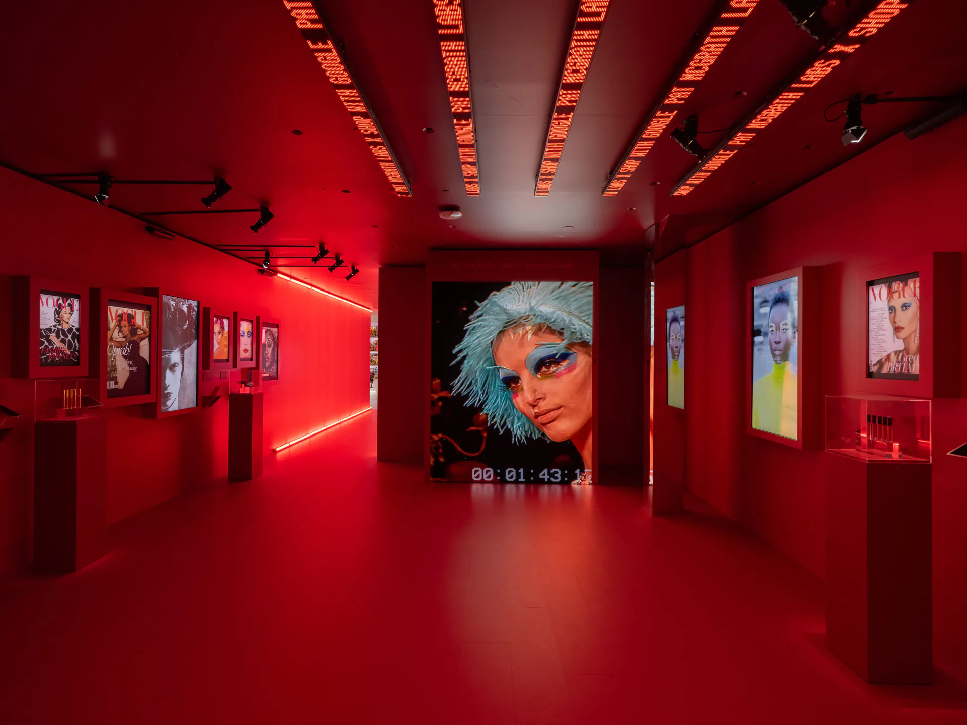Red-walled gallery exhibition space with neon linear lighting, displaying large-scale portrait photography and framed artworks by Bednark Studio.