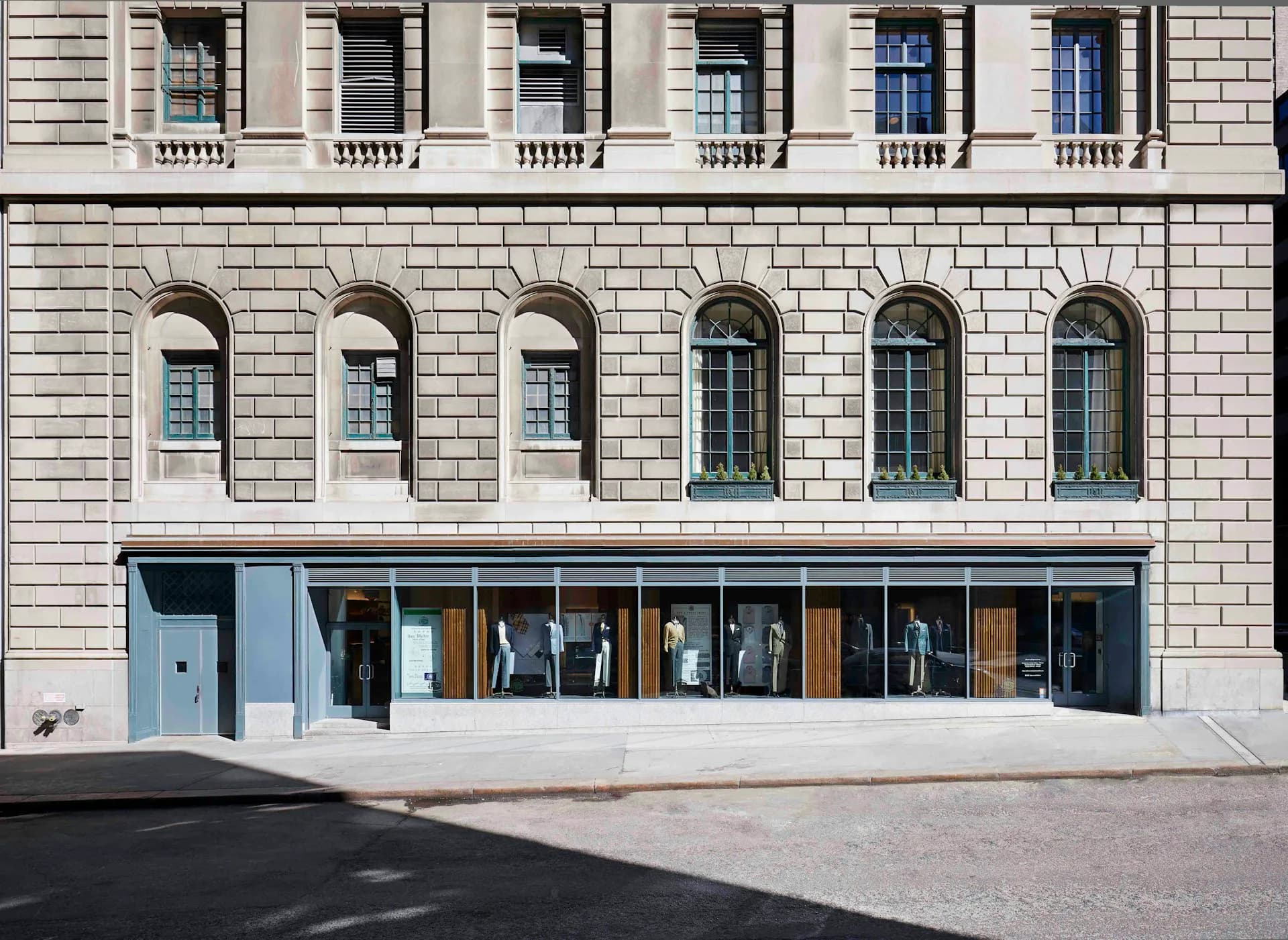 Neoclassical building facade with arched windows above a modern storefront with blue-gray framing and glass doors by Belmont Freeman Architects.