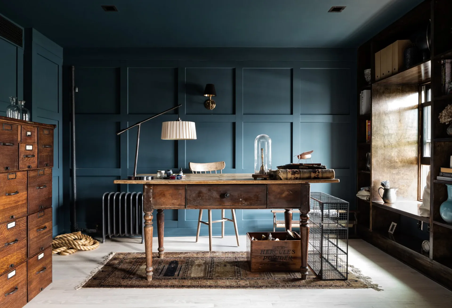 Dark teal office with wooden desk, vintage filing cabinets, pendant lighting, and industrial shelving by Bespoke Only.