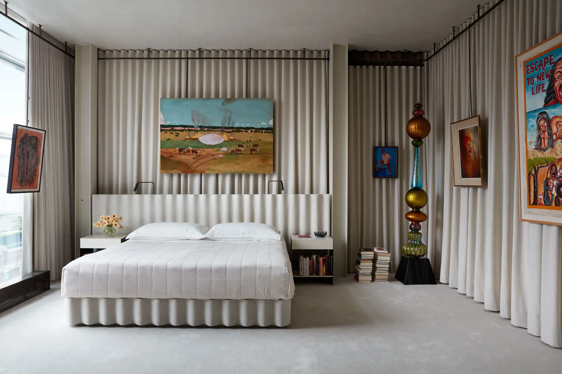 Modern bedroom with ribbed corrugated metal walls, platform bed with white bedding, colorful artwork, and sheer curtains by Billy Cotton Studio.