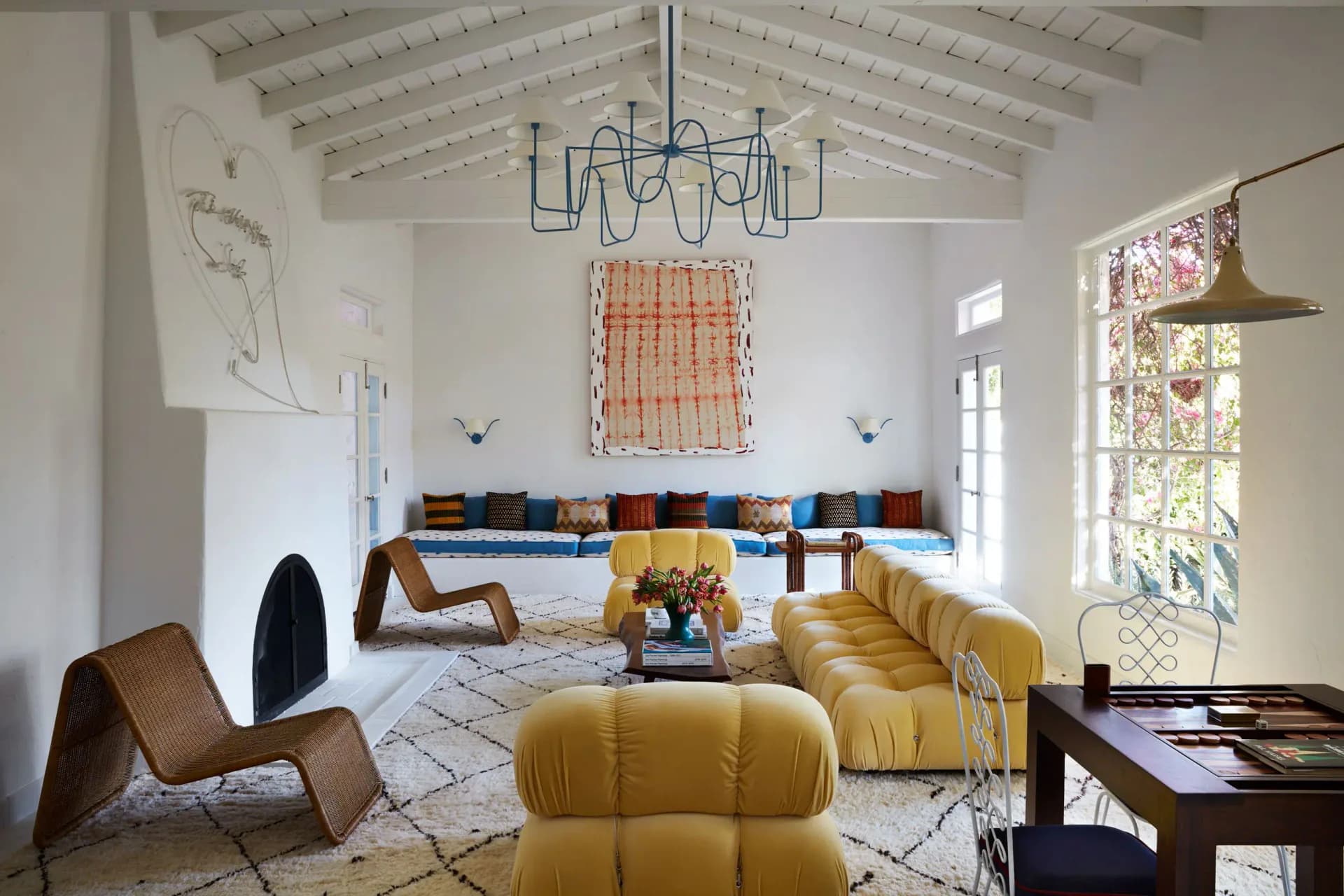 Bright modernist living room with yellow curved sofa, geometric floor pattern, and colorful cushion display by Billy Cotton Studio.
