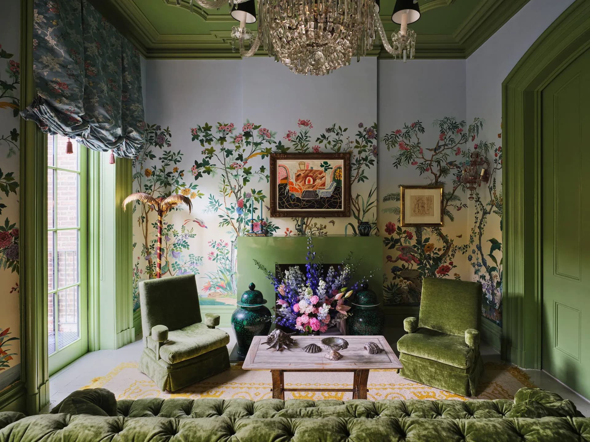 A jewel-toned sitting room featuring botanical wallpaper, green lacquered doors and ceiling, vintage furniture, and purple floral arrangement by Billy Cotton Studio.