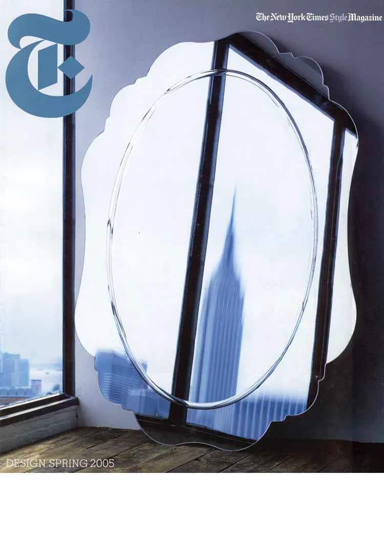Modern mirror installation with black frame reflecting Manhattan skyline, positioned in bright interior space by Bitnar Architects.