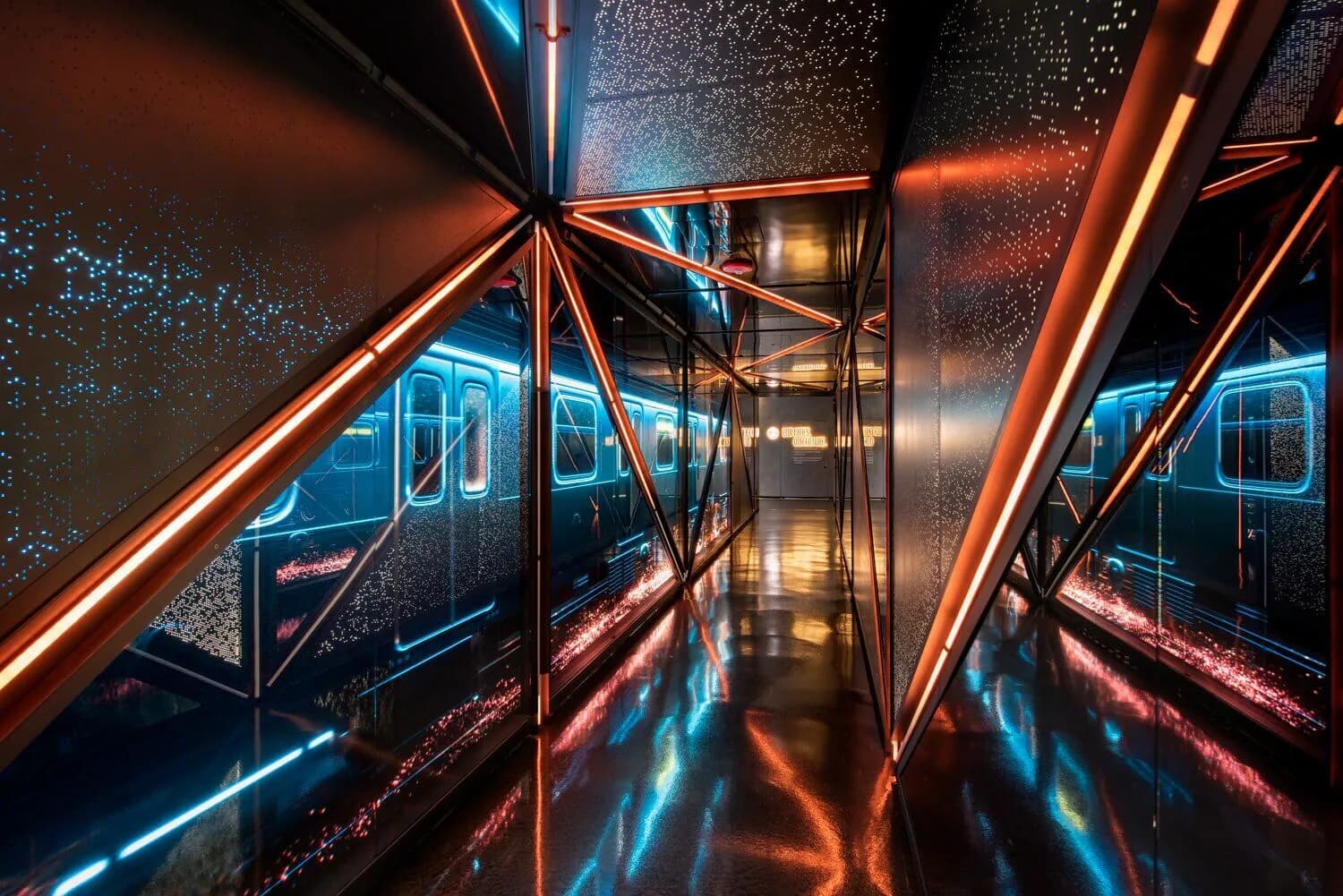 Neon-lit subway or train corridor with glowing orange and blue linear elements reflecting on wet surfaces, creating a symmetrical futuristic atmosphere by BOLD (Brian Orter Lighting Design).