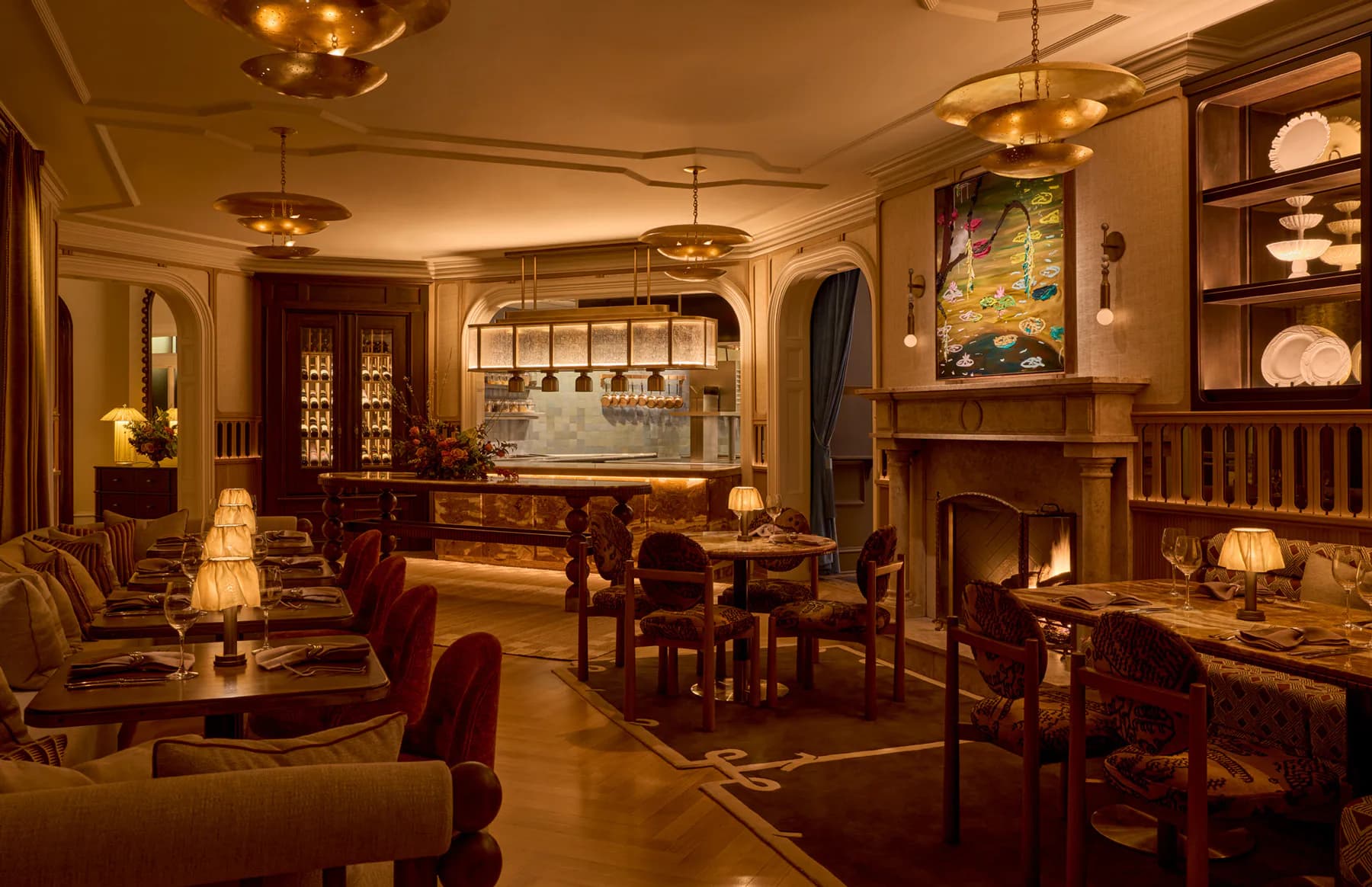 Warm-toned residential lounge featuring custom lighting design with brass fixtures, wood cabinetry, fireplace, and layered ambient illumination throughout the space by BOLD (Brian Orter Lighting Design).
