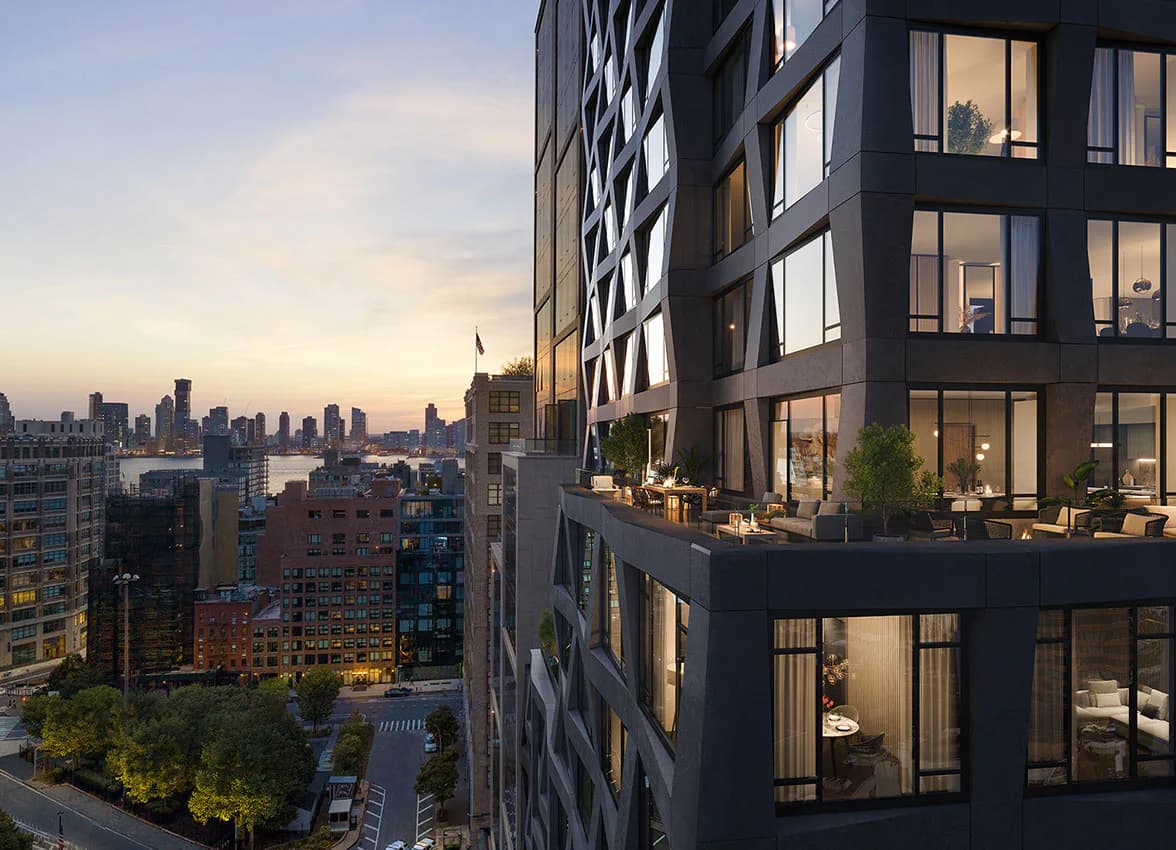 Modern high-rise residential building at dusk with illuminated interior spaces, Manhattan skyline visible in background, designed by BOLD (Brian Orter Lighting Design).