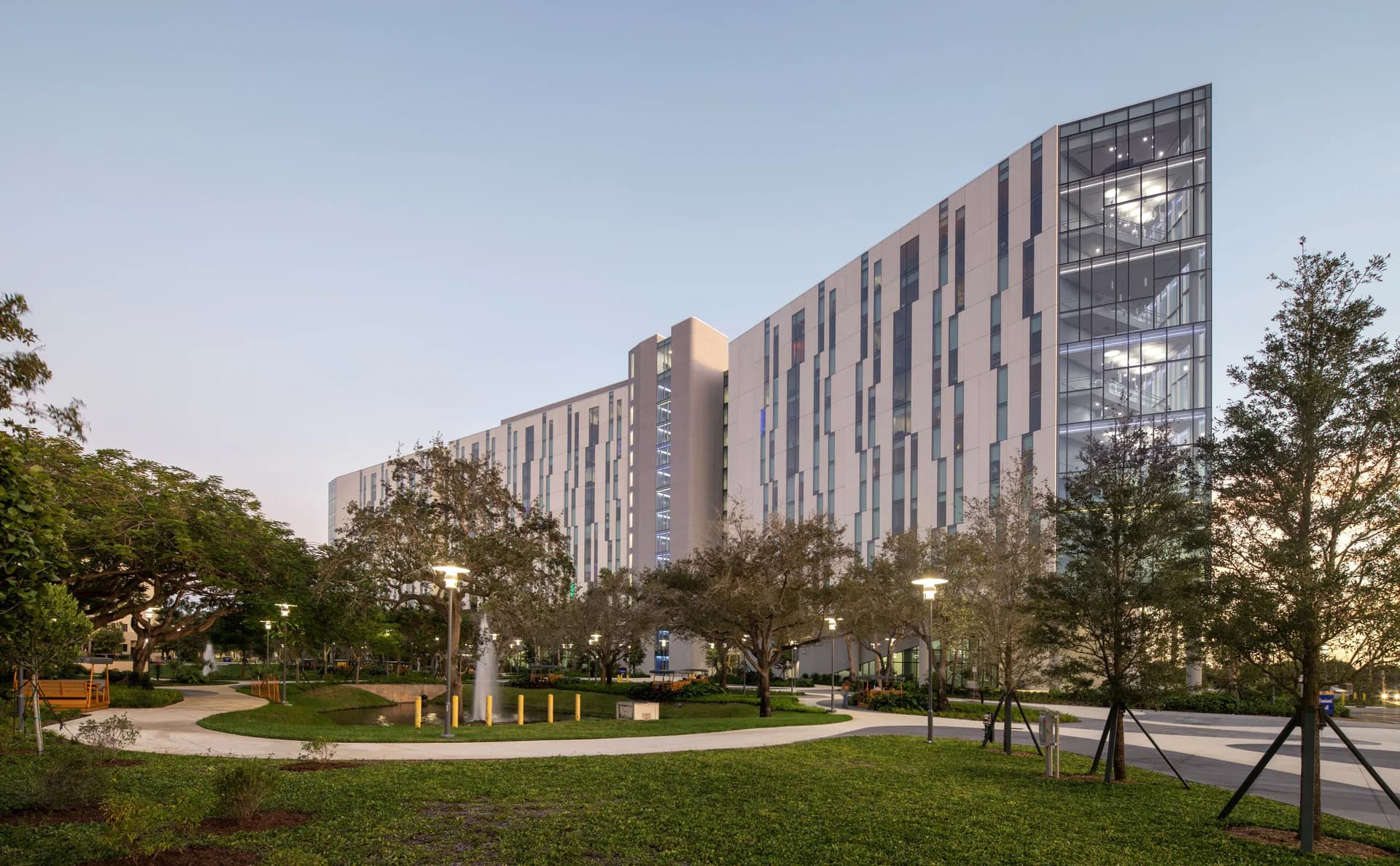 Modern residential complex with curved plaza, green landscaping, and contemporary tower featuring integrated lighting design by Borealis Lighting Studio (BR+A Consulting Engineers).