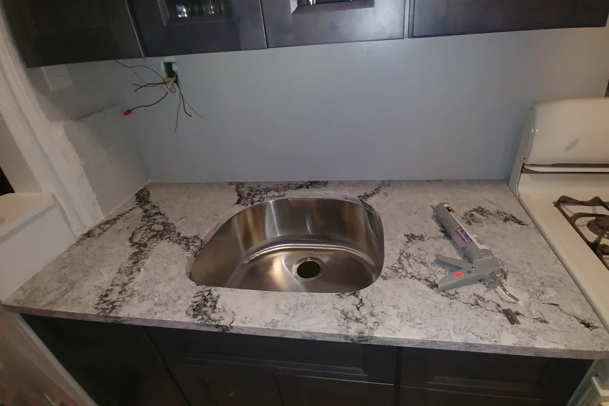 Kitchen countertop in light gray marble with black veining featuring a circular stainless steel undermount sink by Brooklyn Stone & Tile.