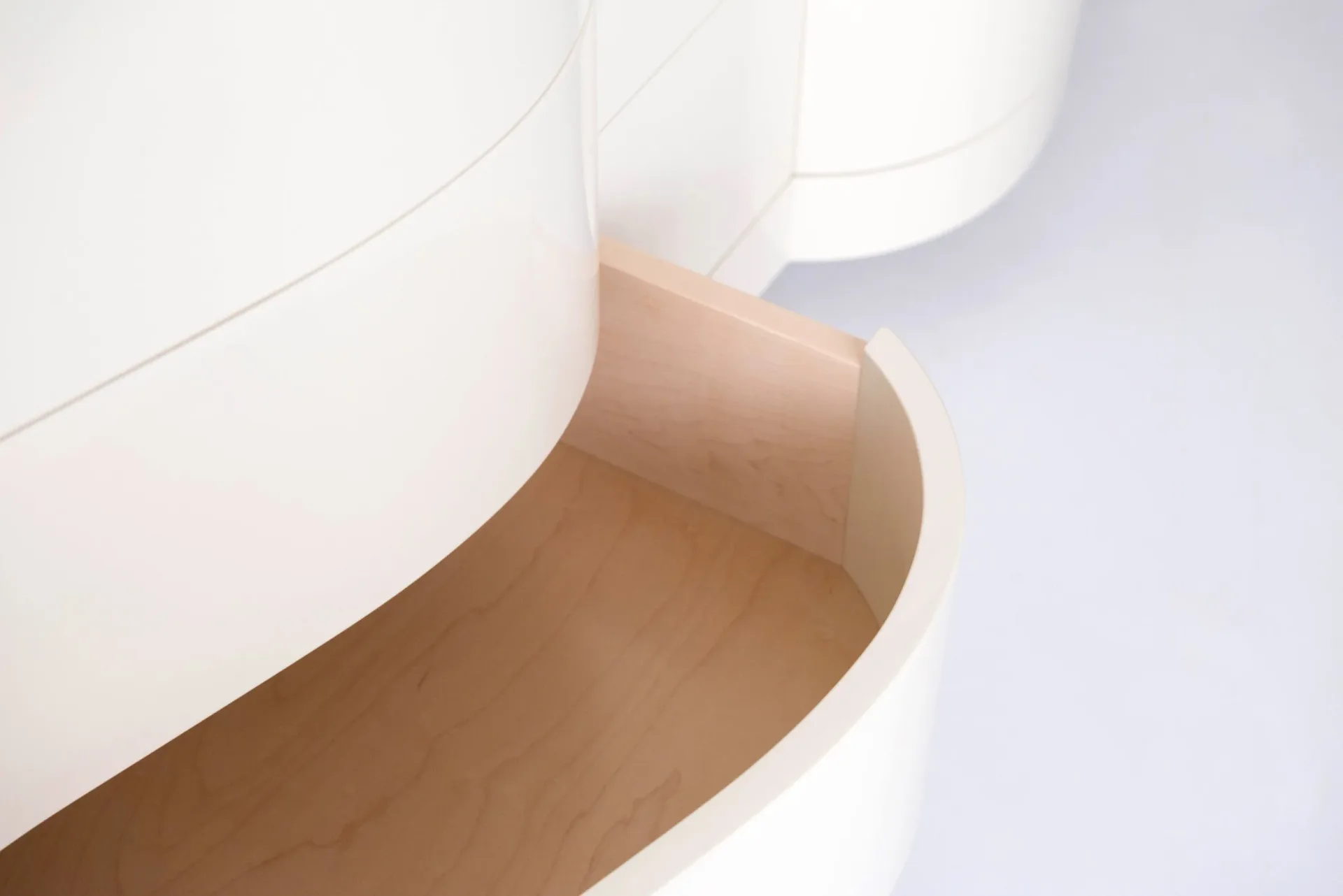 Close-up detail of curved white architectural elements with warm wood tones, showcasing material transitions and geometric forms by Built By Steel.
