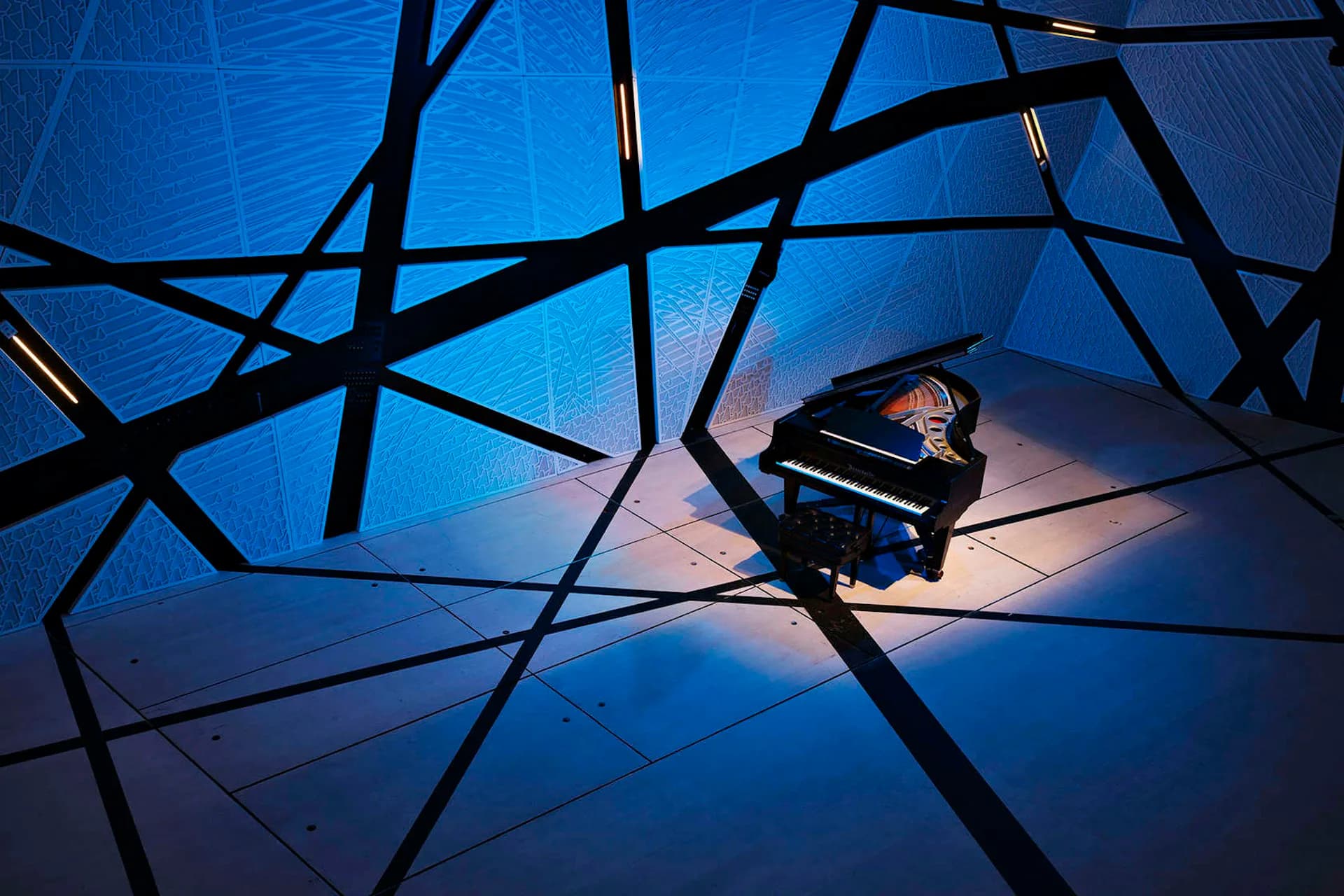 Abstract architectural interior with geometric black beam structures intersecting across a luminous blue gradient space, featuring a grand piano, designed by Bureau V.