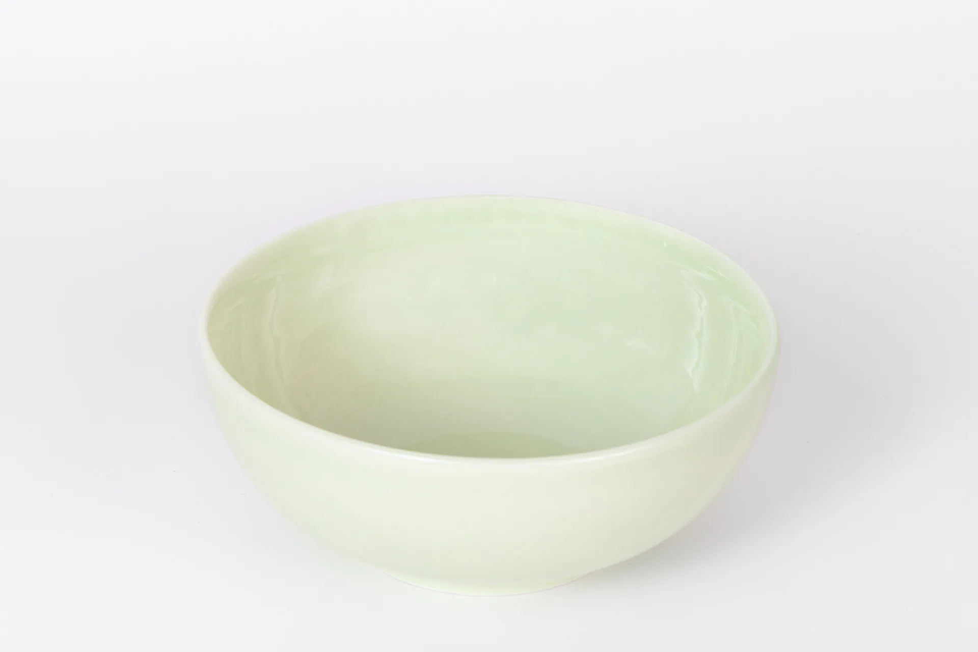 Pale green ceramic bowl with smooth, curved walls and matte glaze finish, photographed against a neutral background by CAL Ceramics.