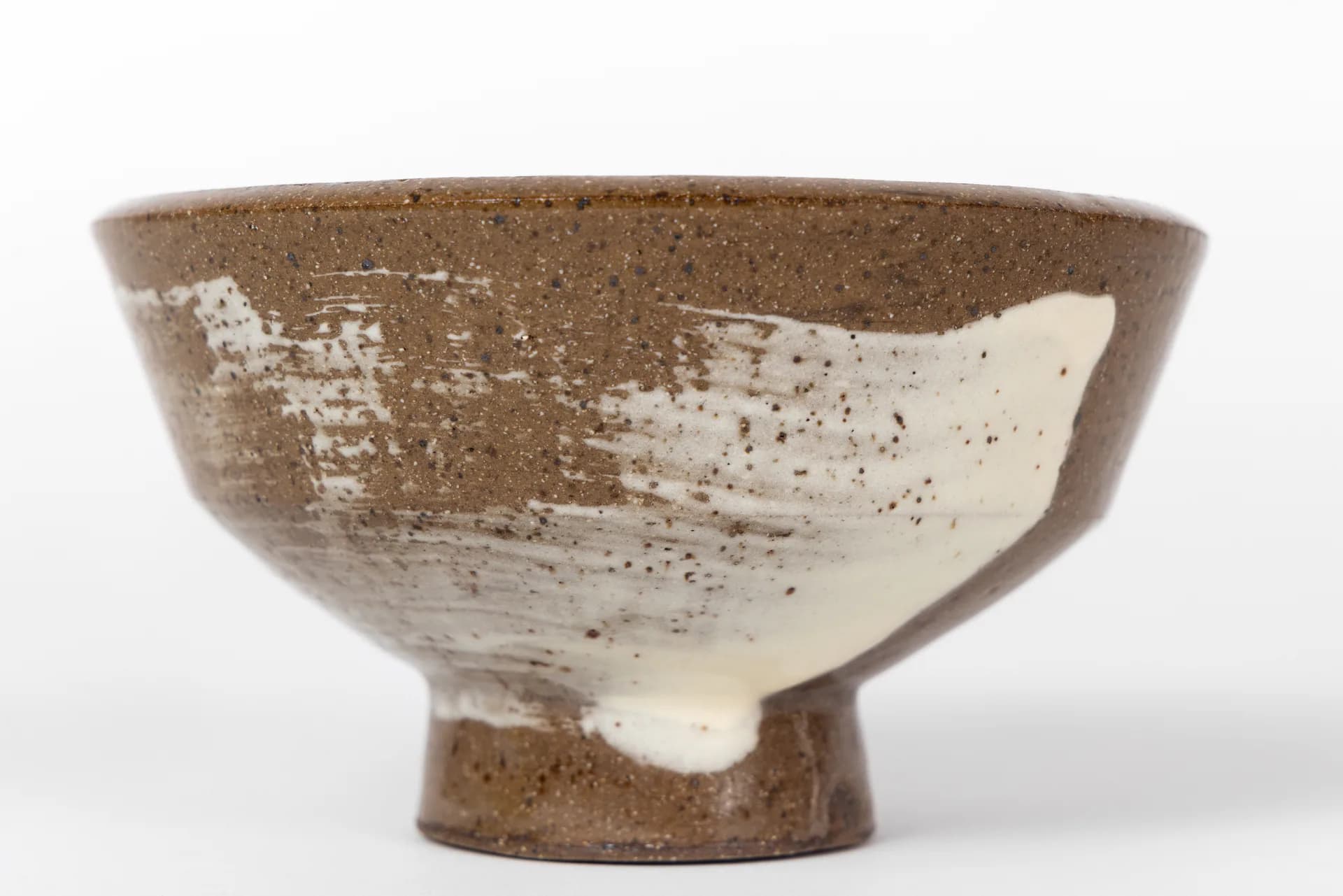 Handcrafted ceramic bowl with earthy brown glaze and cream-colored brushed accent, featuring organic texture and pedestal base by CAL Ceramics.
