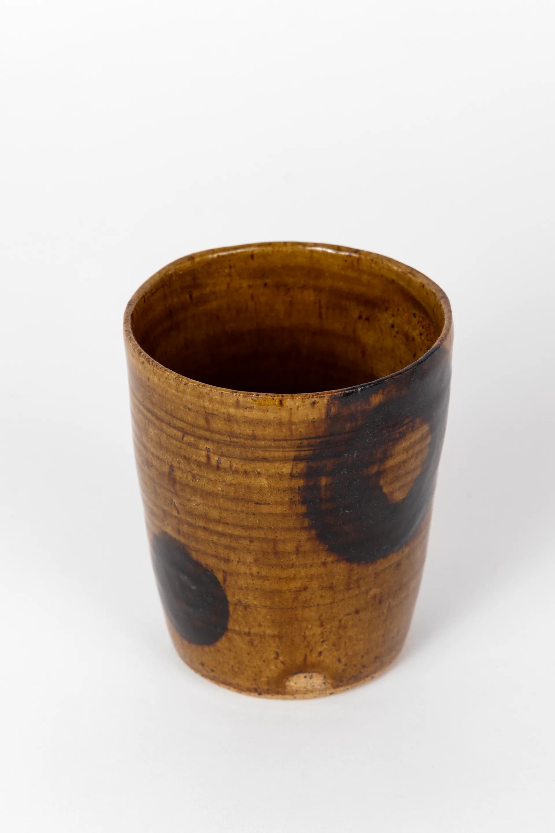 Cylindrical ceramic vessel with warm terracotta glaze and dark brown accents, displaying organic surface texture by CAL Ceramics.