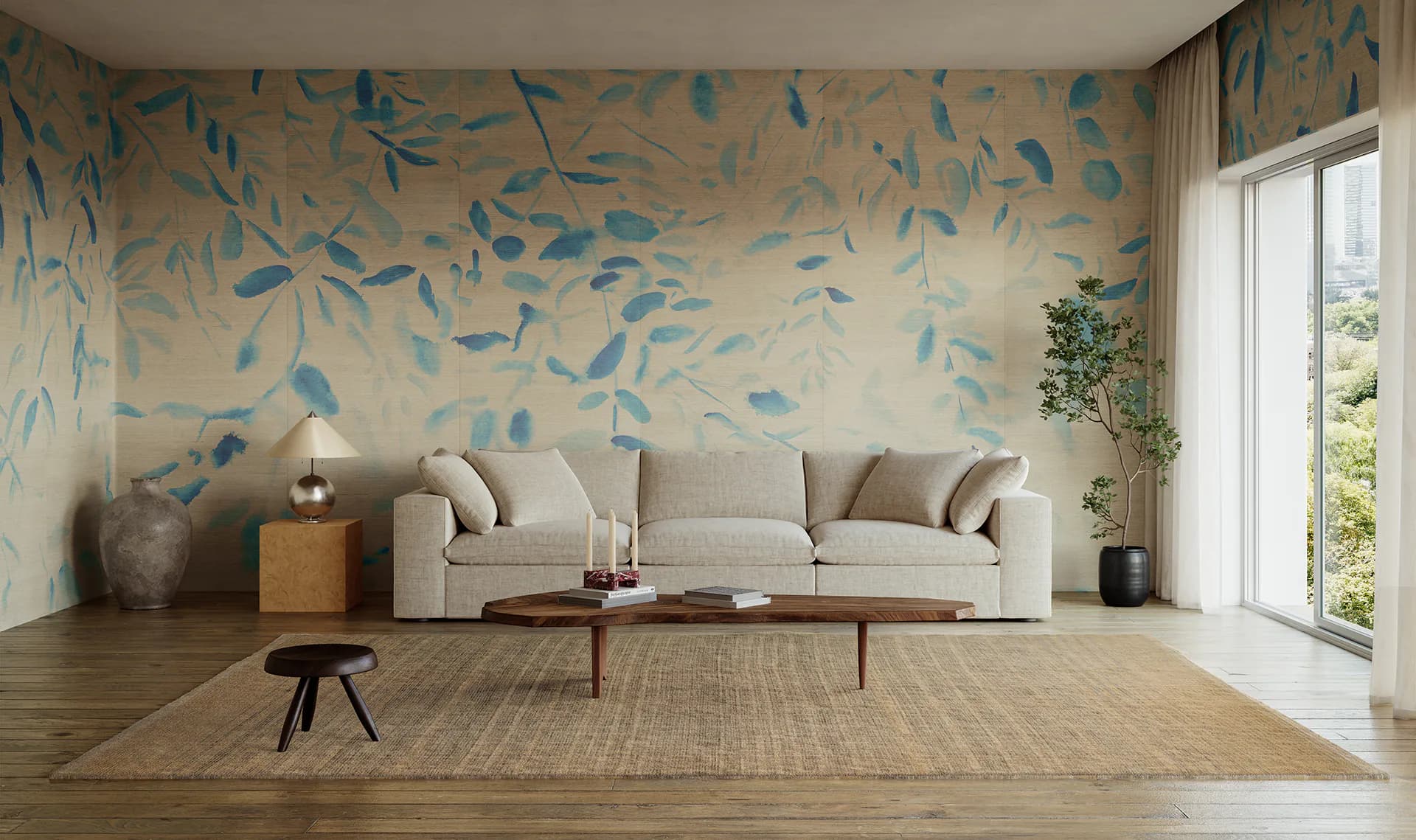 Modern living room with cream sofa, wooden coffee table, and feature wall decorated with blue leaf-patterned wallpaper by Calico Wallpaper.