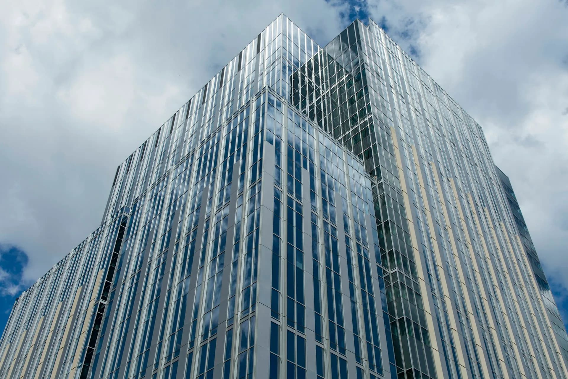 Tall modern office building with vertical striping and glass facade against cloudy sky, designed by CannonDesign.