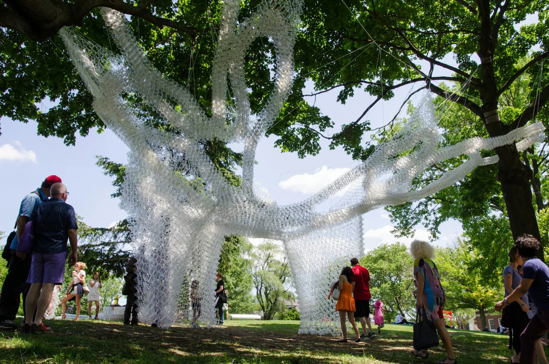 Large-scale white mesh sculptural installation of an abstract figure in a park setting surrounded by trees and visitors, by CDR Studio Architects, PC.
