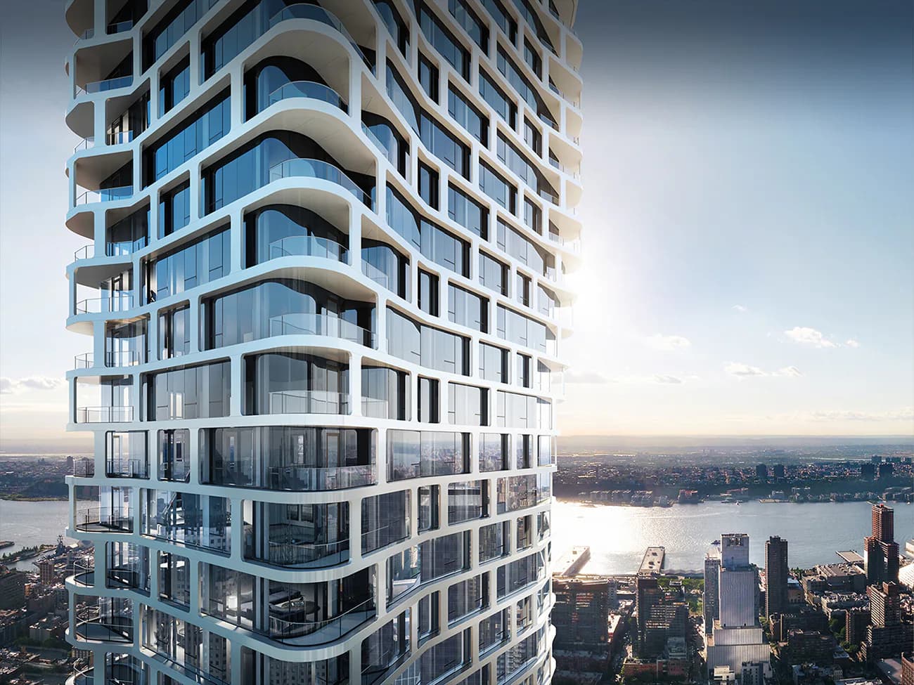 Tall residential tower with curved balconies and gridded facade overlooking a city waterfront, by CetraRuddy.