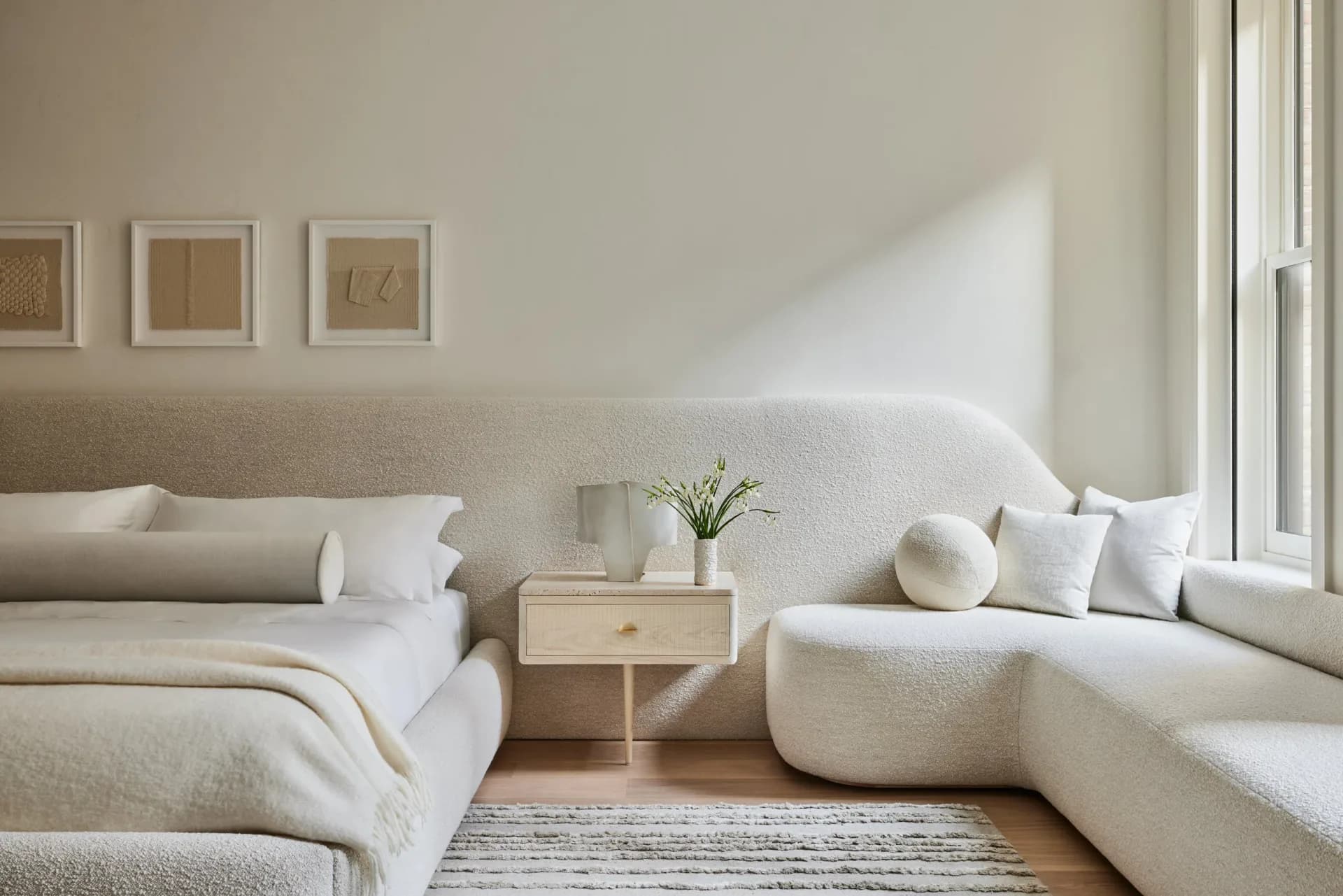 Serene cream-toned bedroom with neutral furnishings, sculptural seating, and soft natural light streaming through floor-to-ceiling windows by Chango & Co.