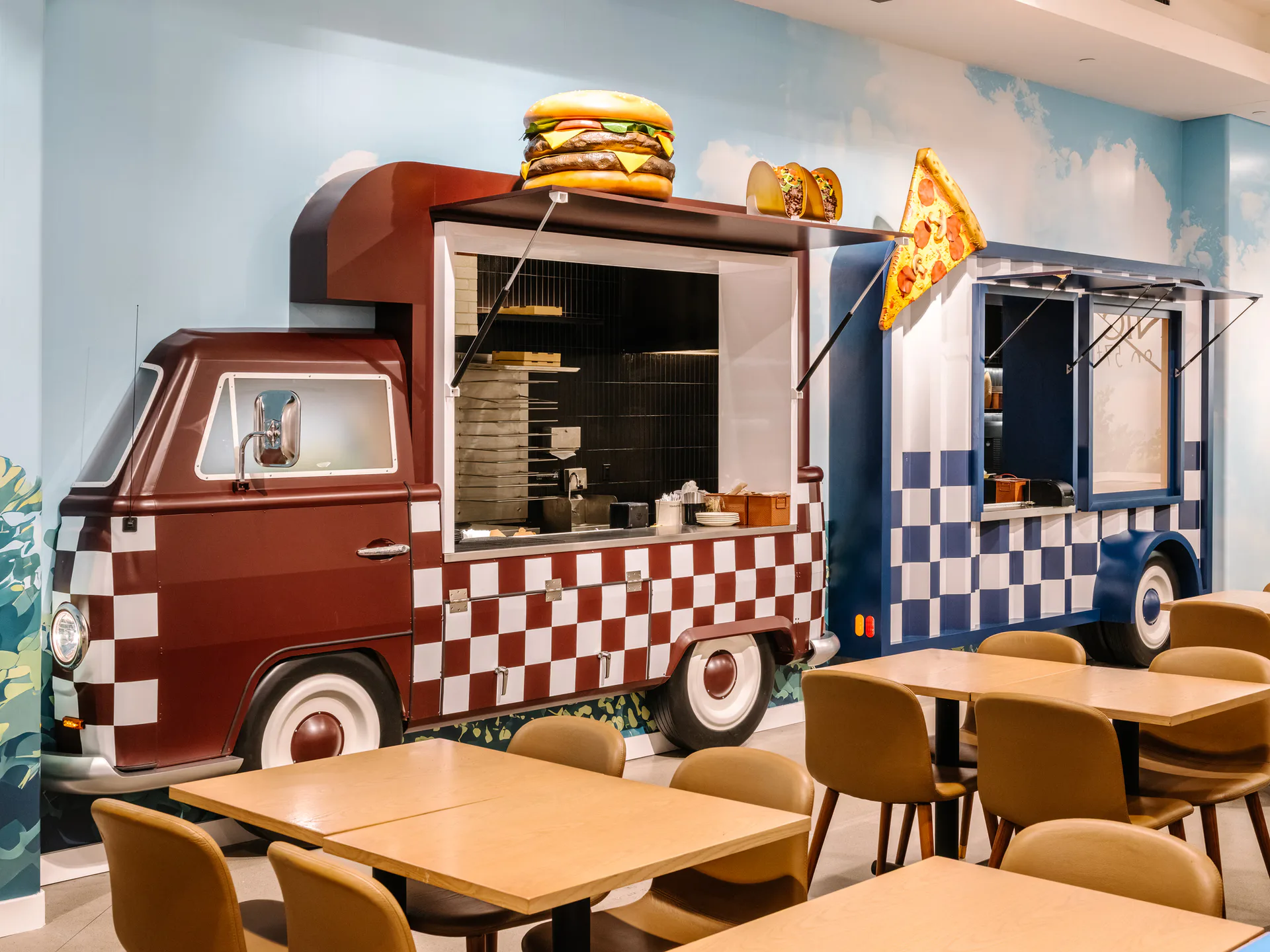 Playful food-truck-themed interior with red and blue checkered custom installations, wooden tables, and tan chairs, designed by Chateau Brooklyn.