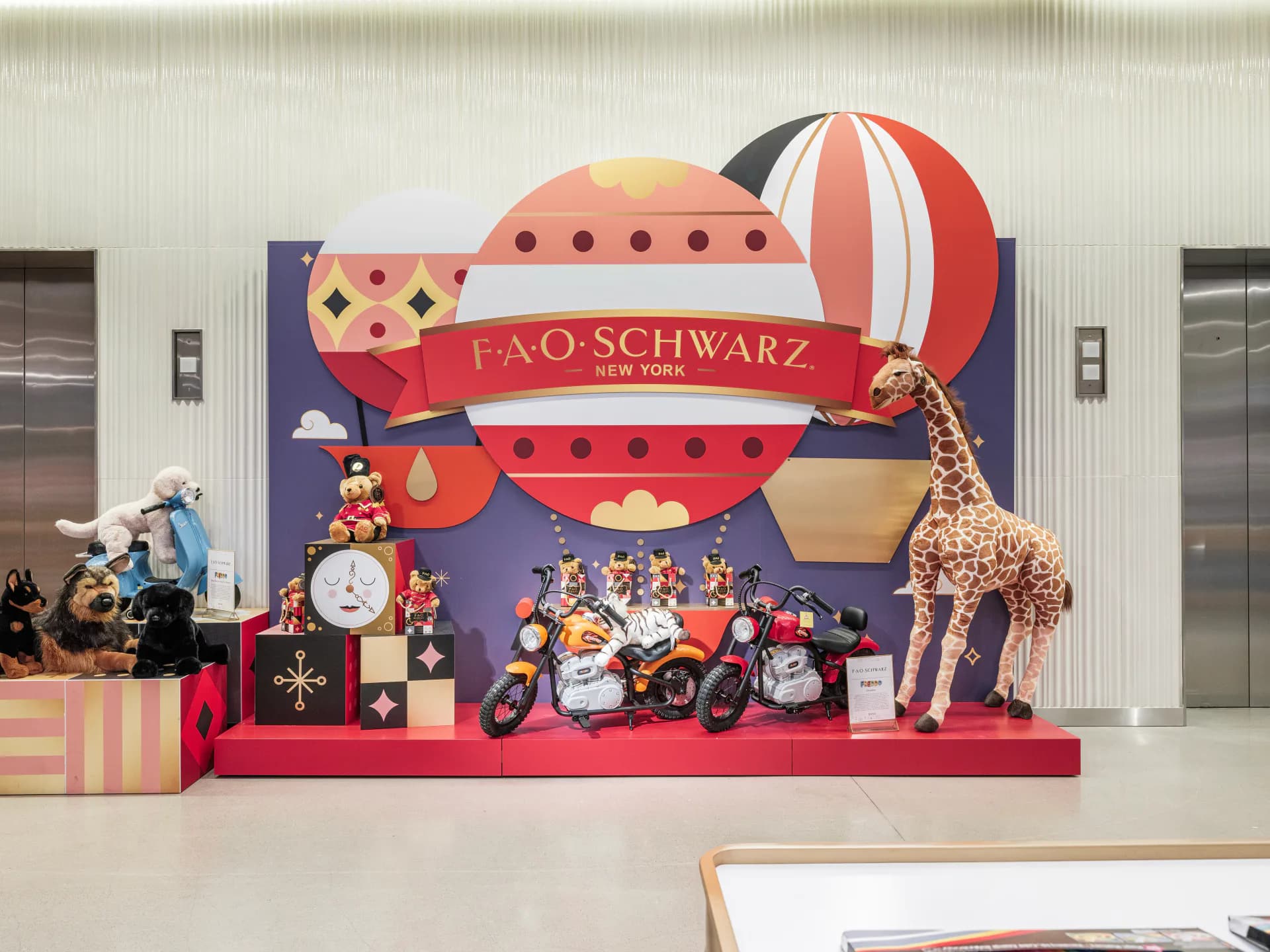 FAO Schwarz holiday window display installation featuring a red hot air balloon, giraffe figure, and festive toy arrangements in a vibrant storefront by Chateau Brooklyn.