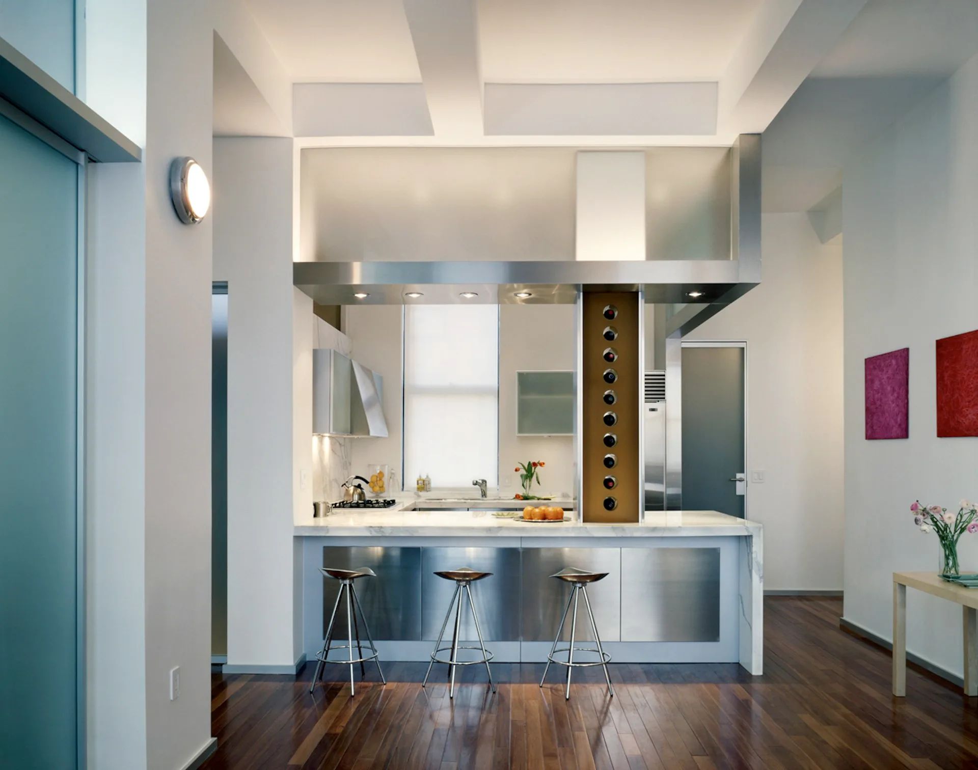 Modern kitchen with waterfall island countertop, three bar stools, floating cabinetry, and geometric ceiling details rendered in soft lighting by Chelsea Atelier Architect, PC.