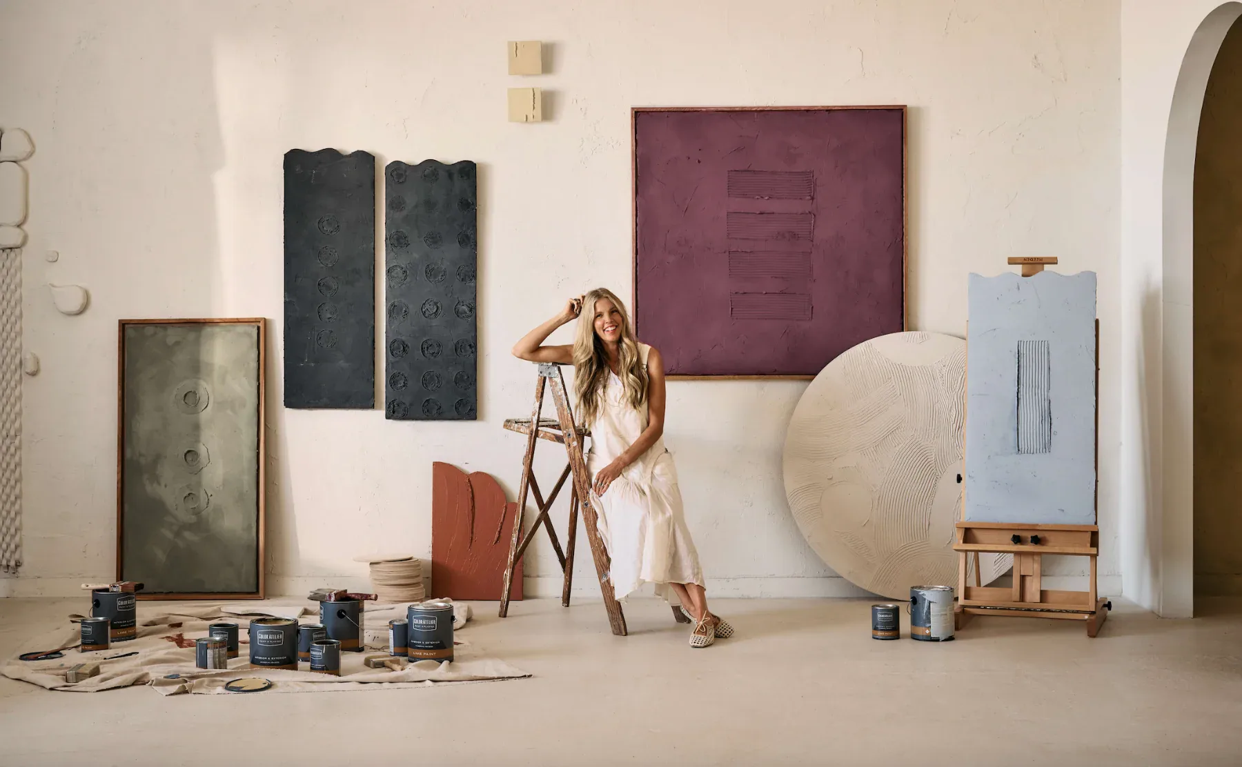 Studio installation with paint samples, wooden easel, circular canvas, and colored panels against neutral walls by Color Atelier.