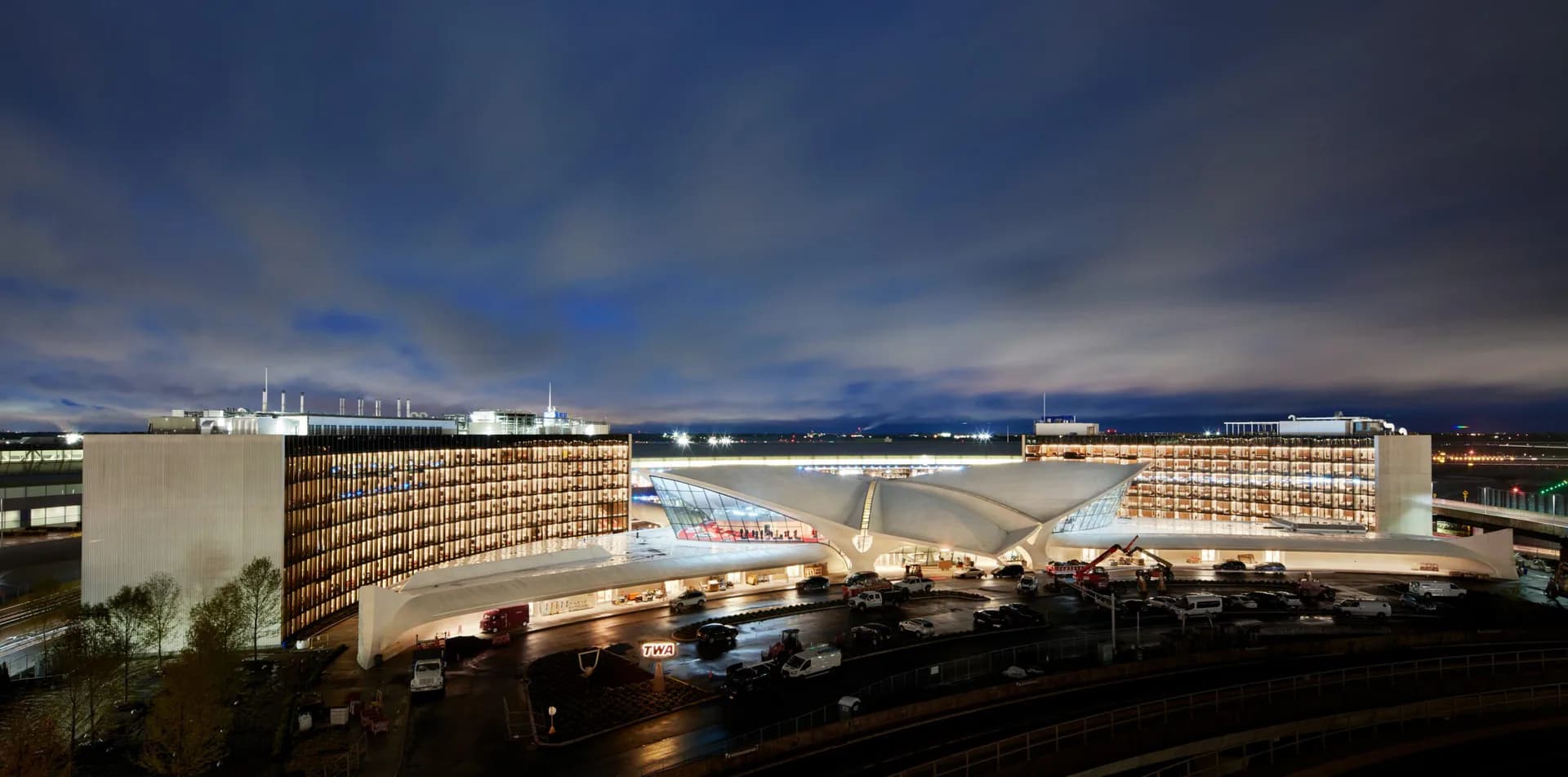 Illuminated modern institutional building with curved brick facade and central atrium courtyard, photographed at dusk by Cooley Monato Studio.