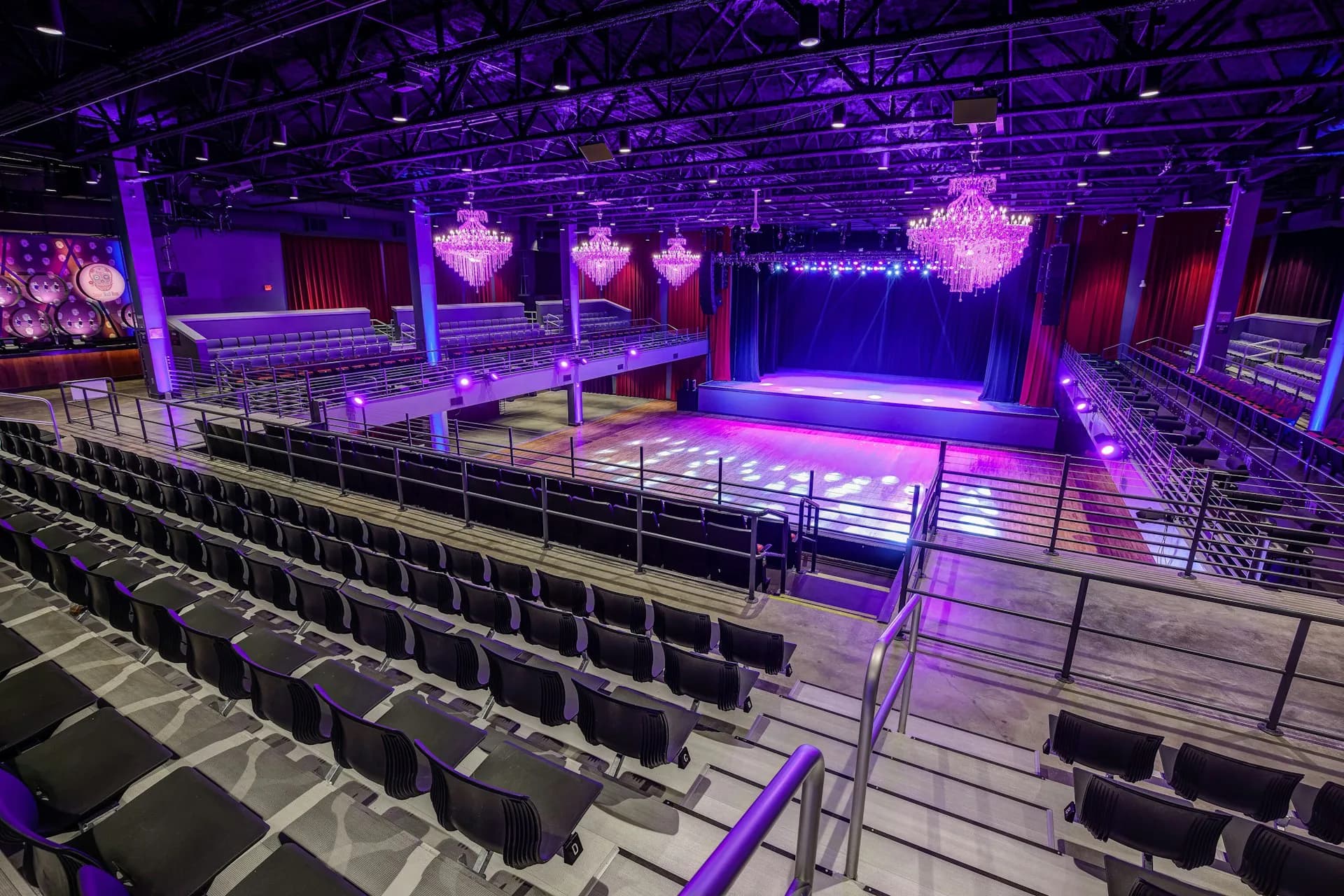 Modern performance venue with purple ambient lighting, tiered seating, and illuminated stage platform designed by Cooper Carry.