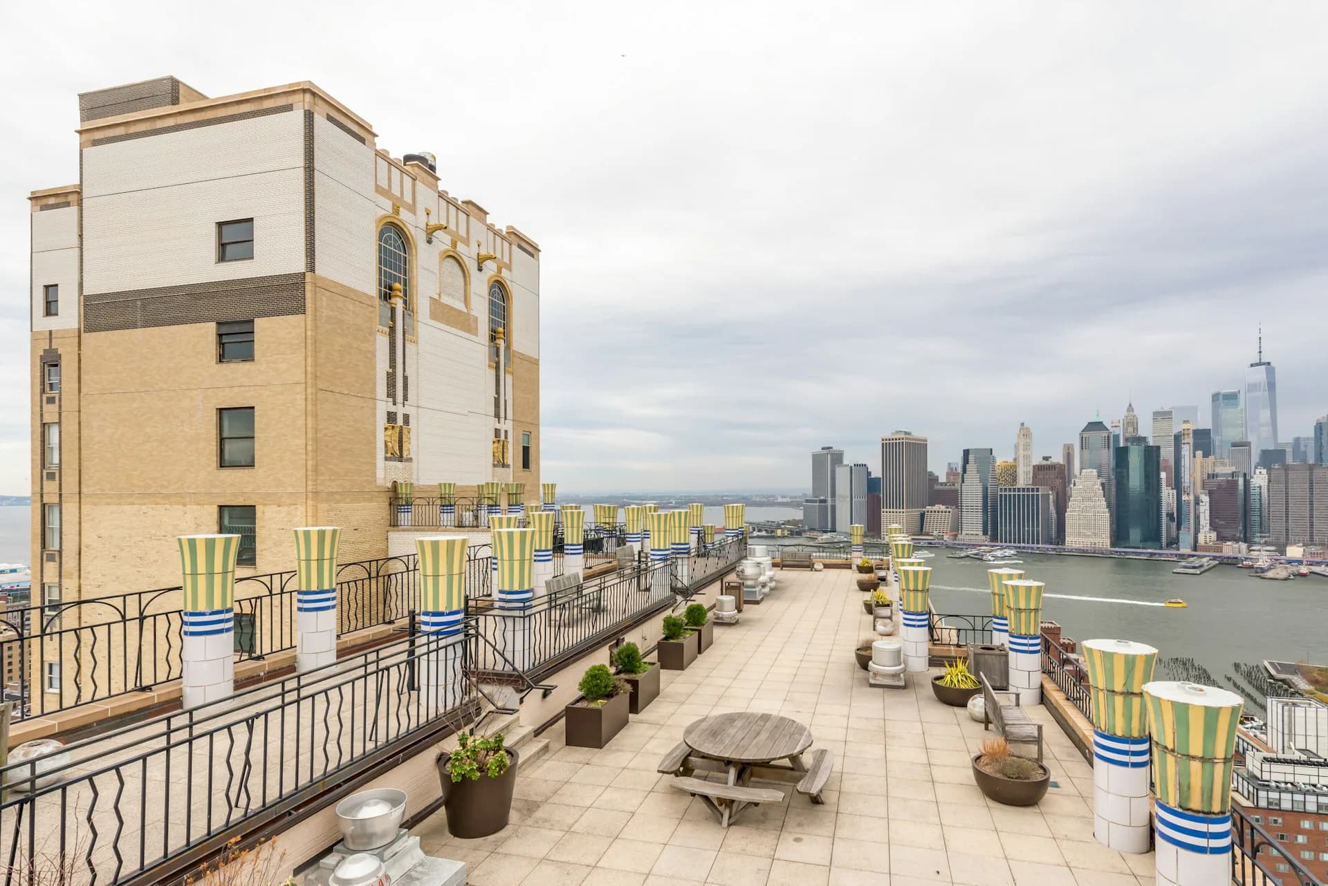 Rooftop terrace with striped lounge chairs, planters, and seating areas overlooking Manhattan skyline, designed by CTA Architects P.C.