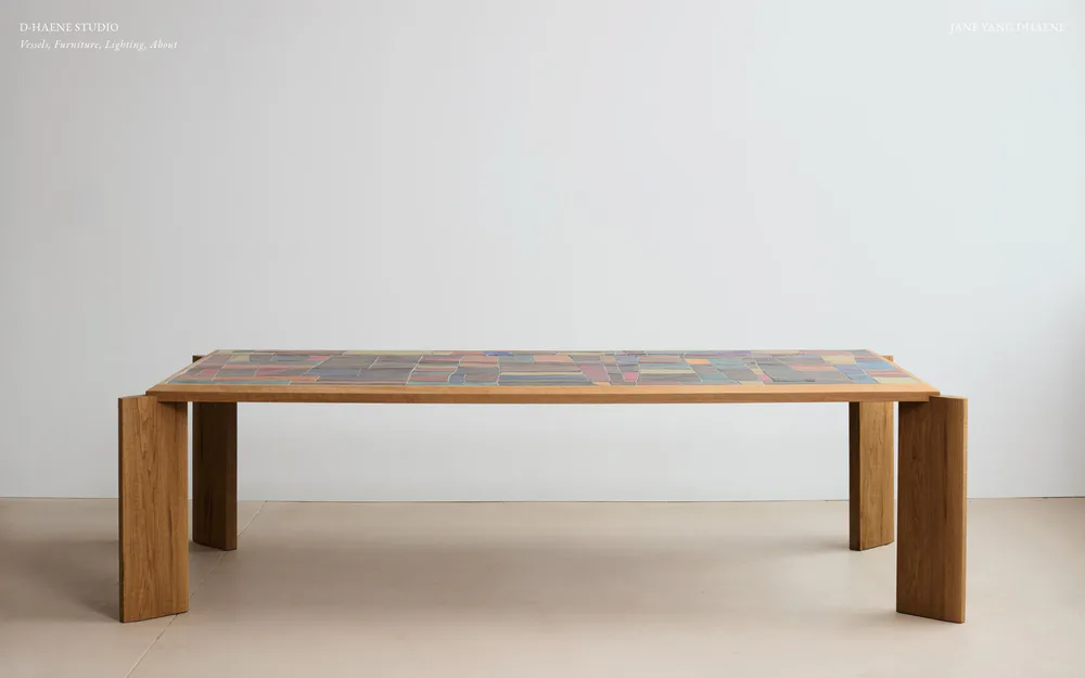 Minimalist wooden dining table with clean geometric design, featuring a light wood frame and textured top, photographed in a neutral studio setting by D-Haene Studio.