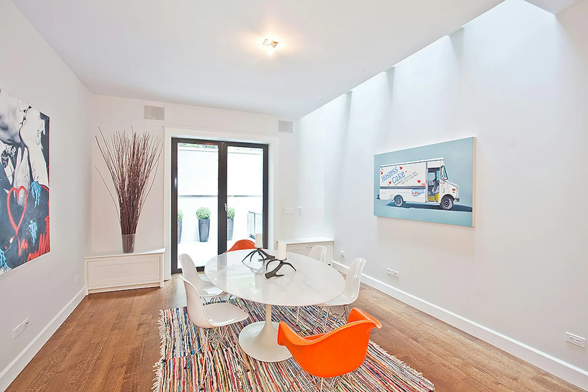 Bright modern living room with white walls, wood flooring, and orange accent chair, designed by Daniel Frisch Architecture.