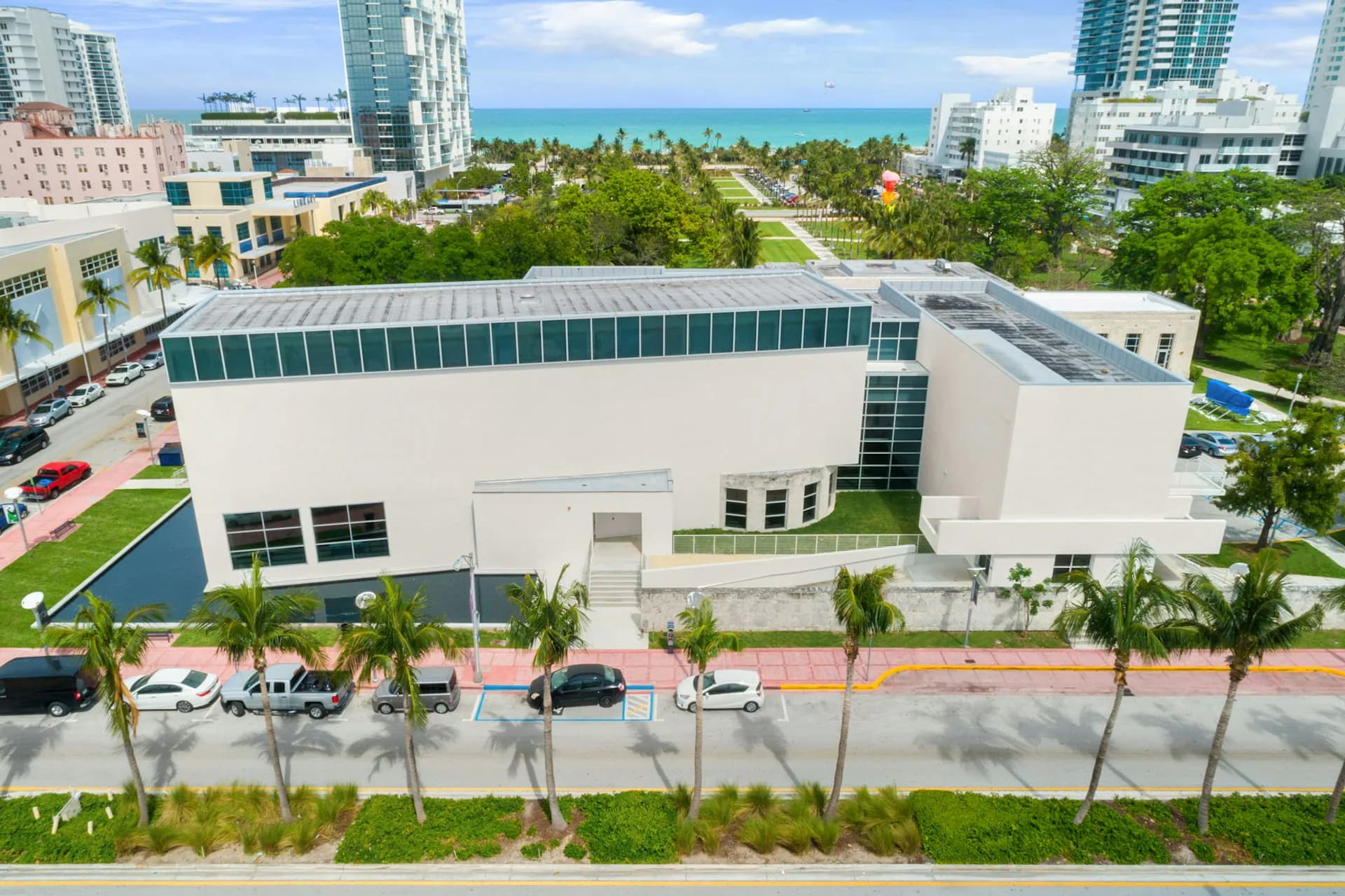 Modern white institutional building with green roof features, palm trees, and ocean view in background by David Gauld Architect.